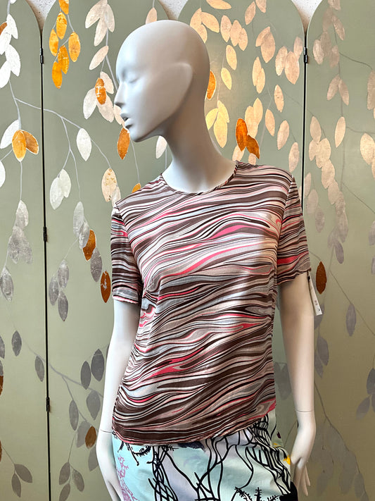 Mannequin wearing a patterned shirt against a decorative wall with leaf designs.