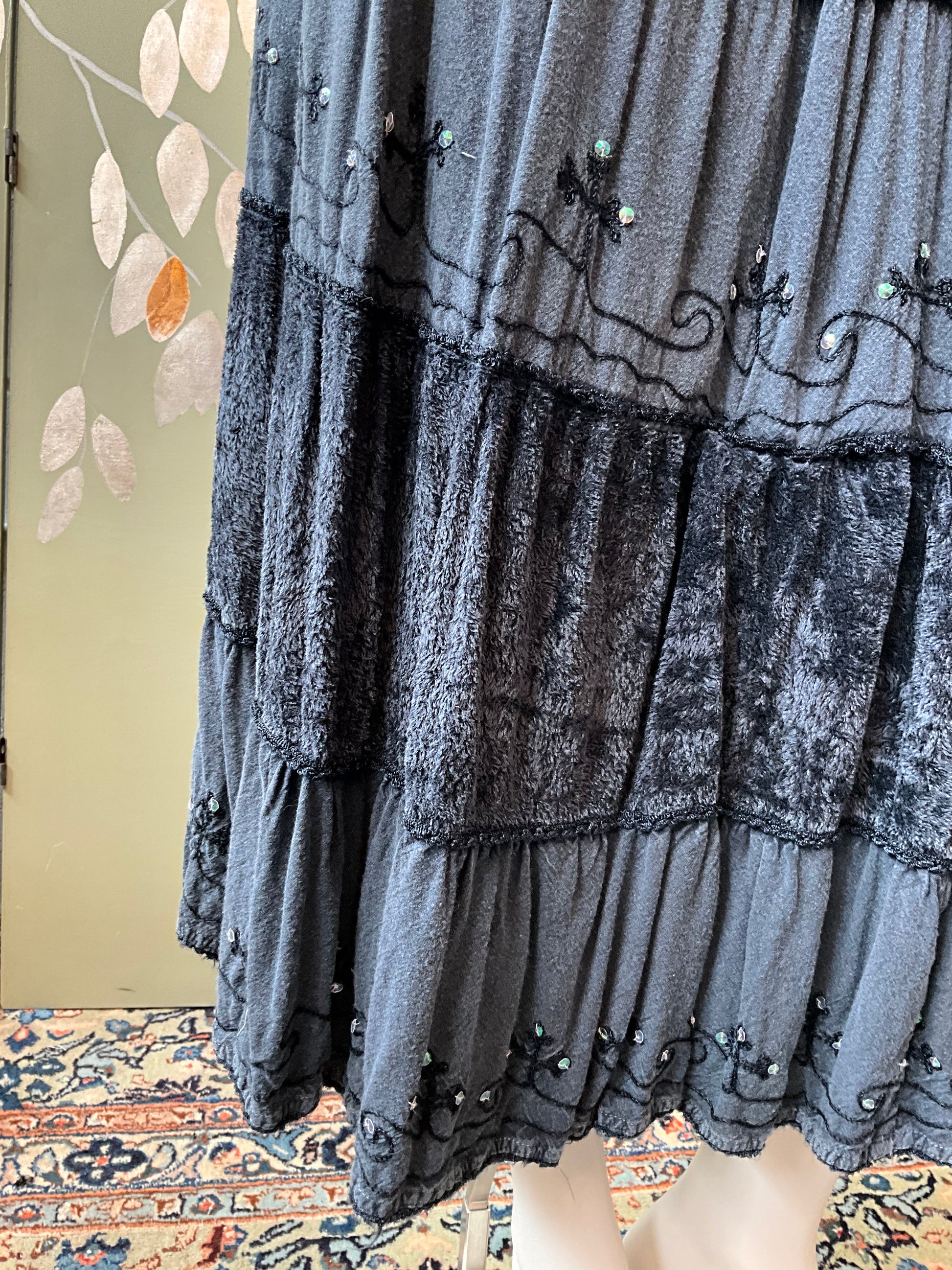Gray textured skirt hem with decorative elements on a patterned rug