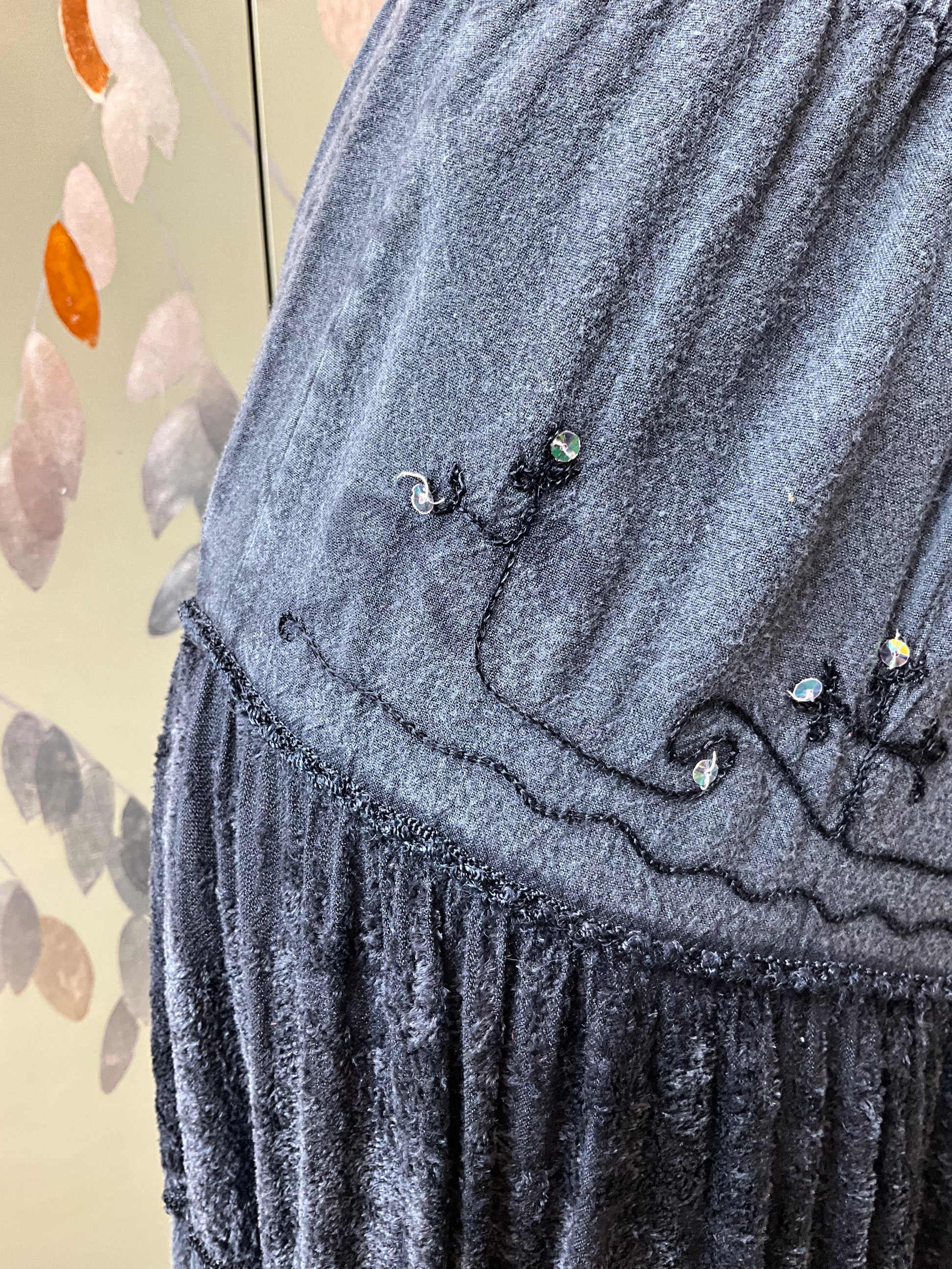 Close-up of a dark gray skirt with decorative elements on a neutral background