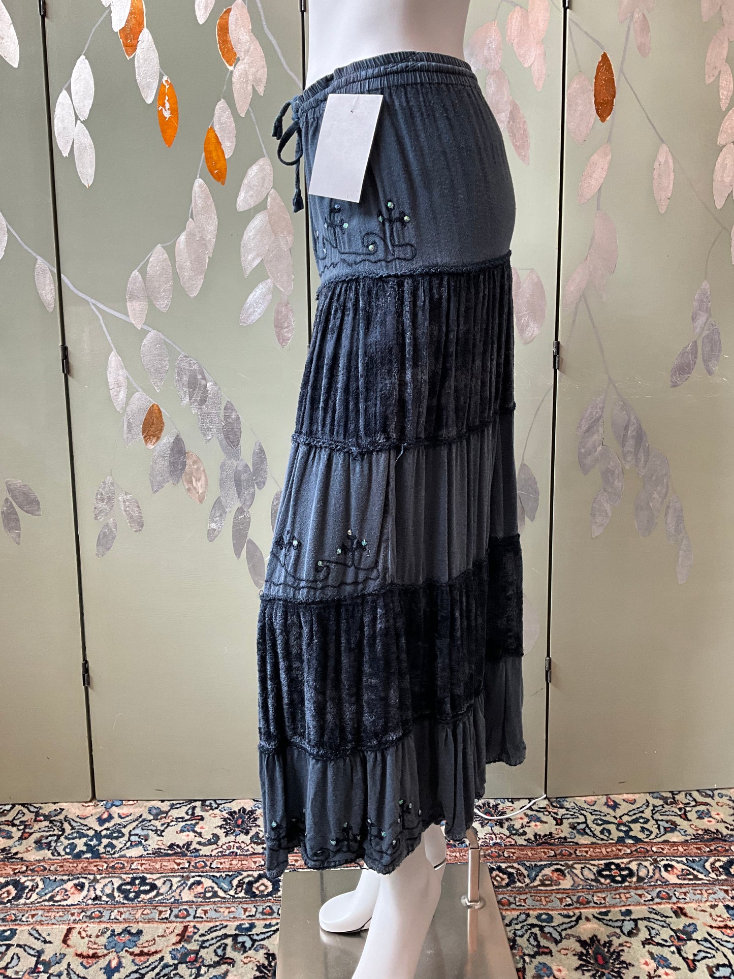 Denim skirt on a mannequin against a floral-patterned wall.