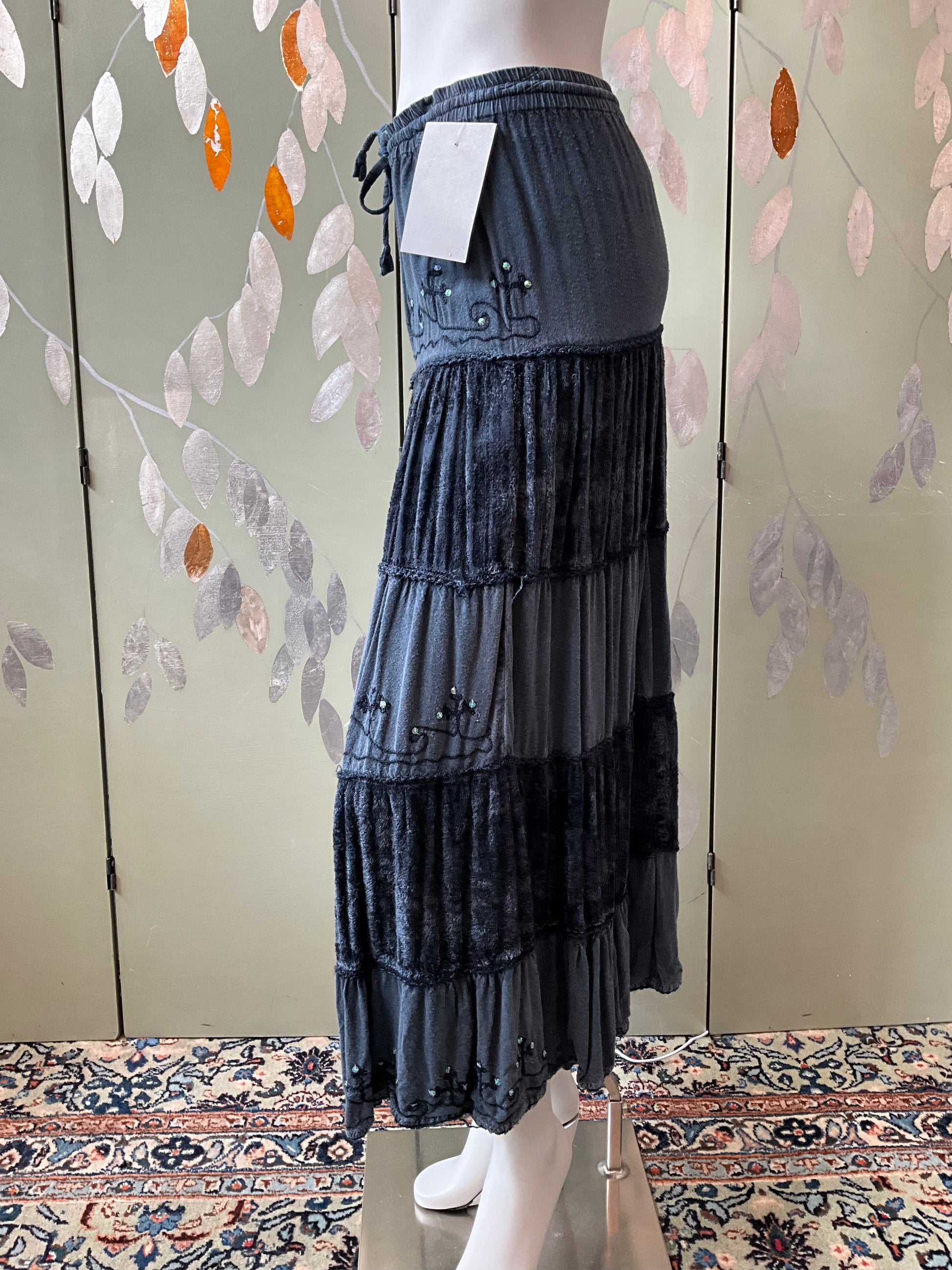 Denim skirt on a mannequin against a floral-patterned wall.