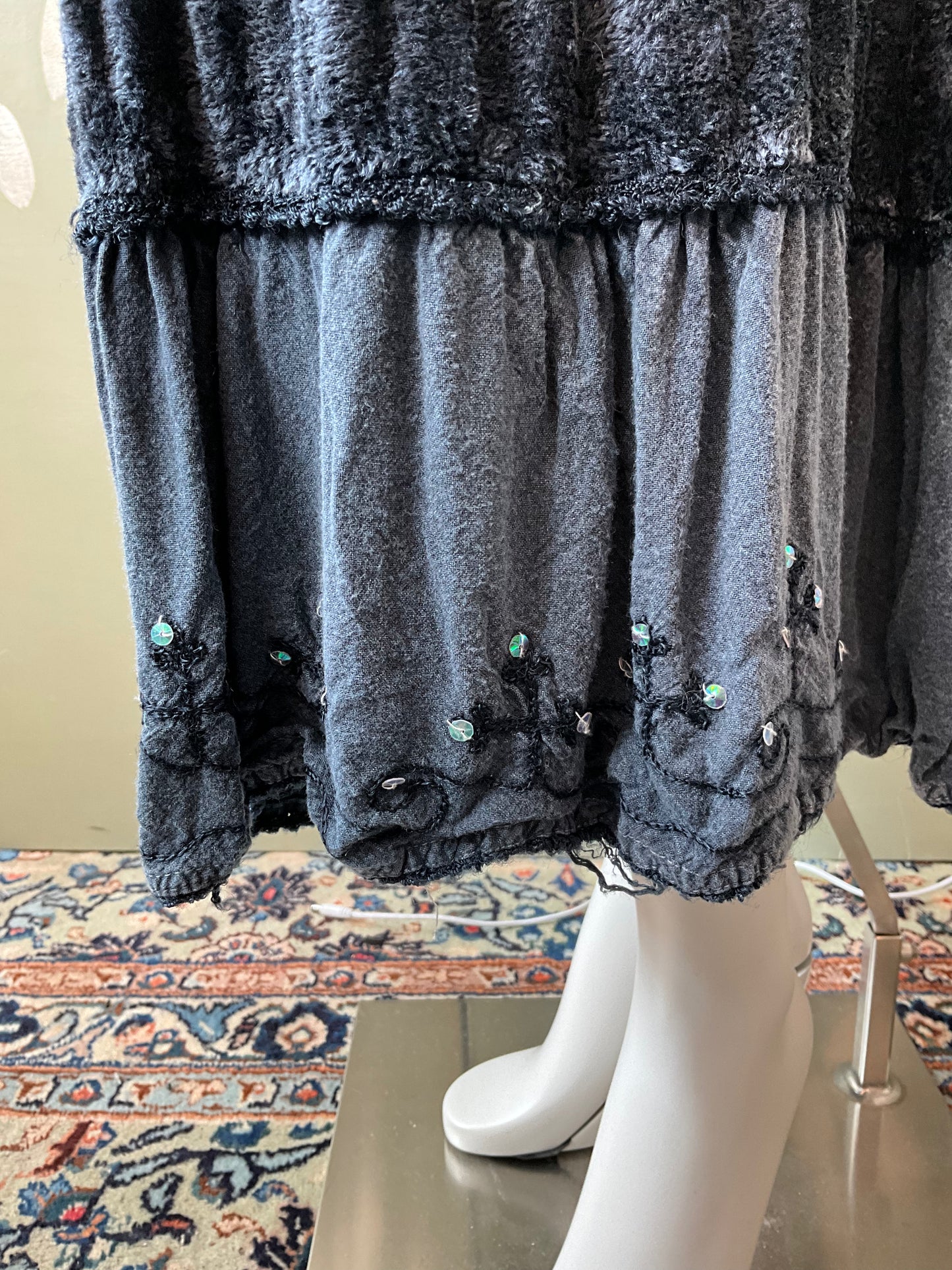 Dark gray skirt hem with lace details on a mannequin against a patterned rug.