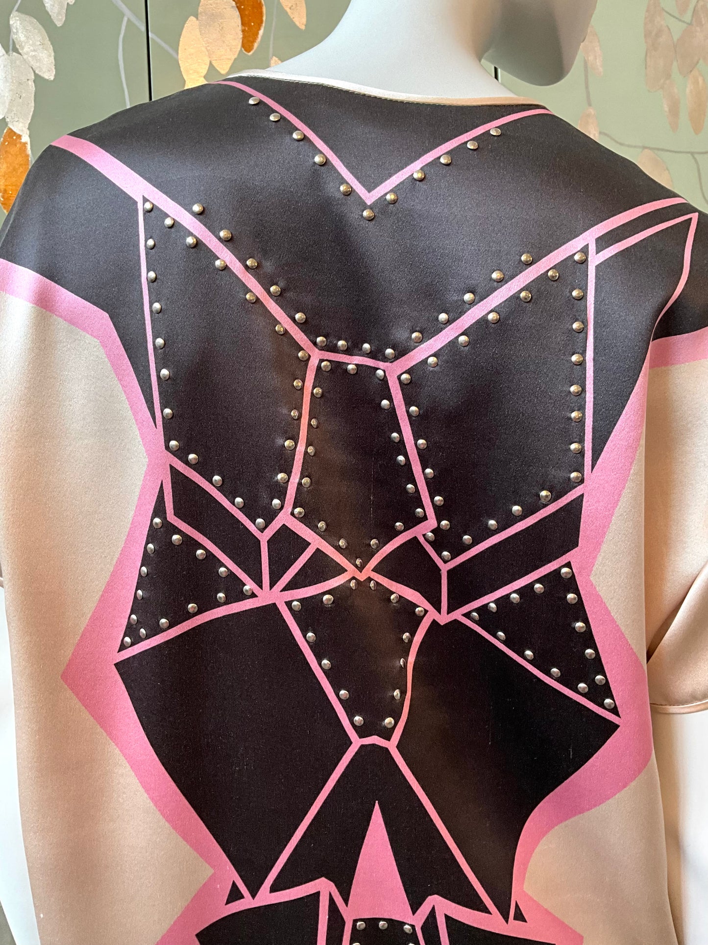 Mannequin wearing a black and pink geometric-patterned garment with studs.