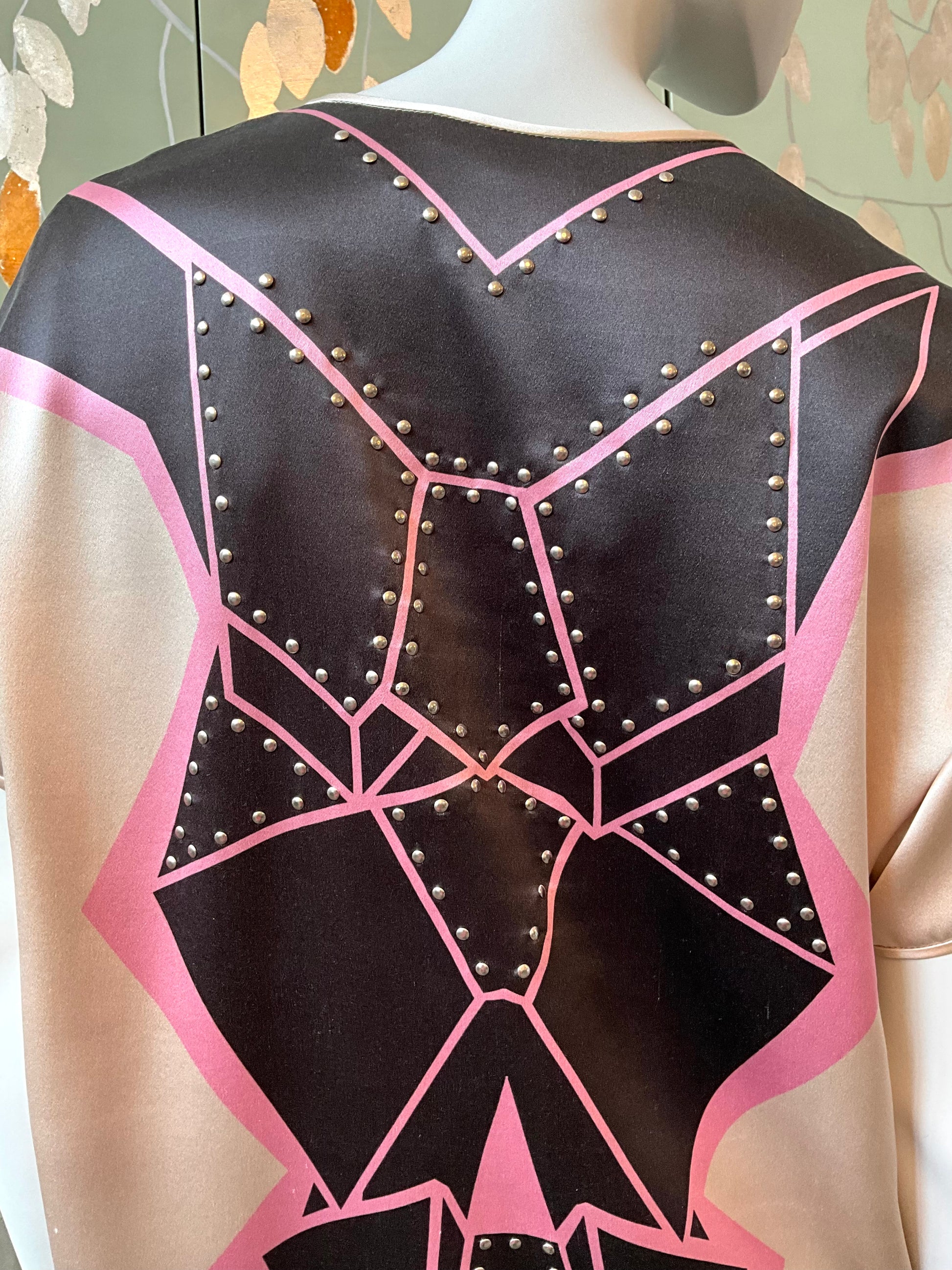 Mannequin wearing a black and pink geometric-patterned garment with studs.