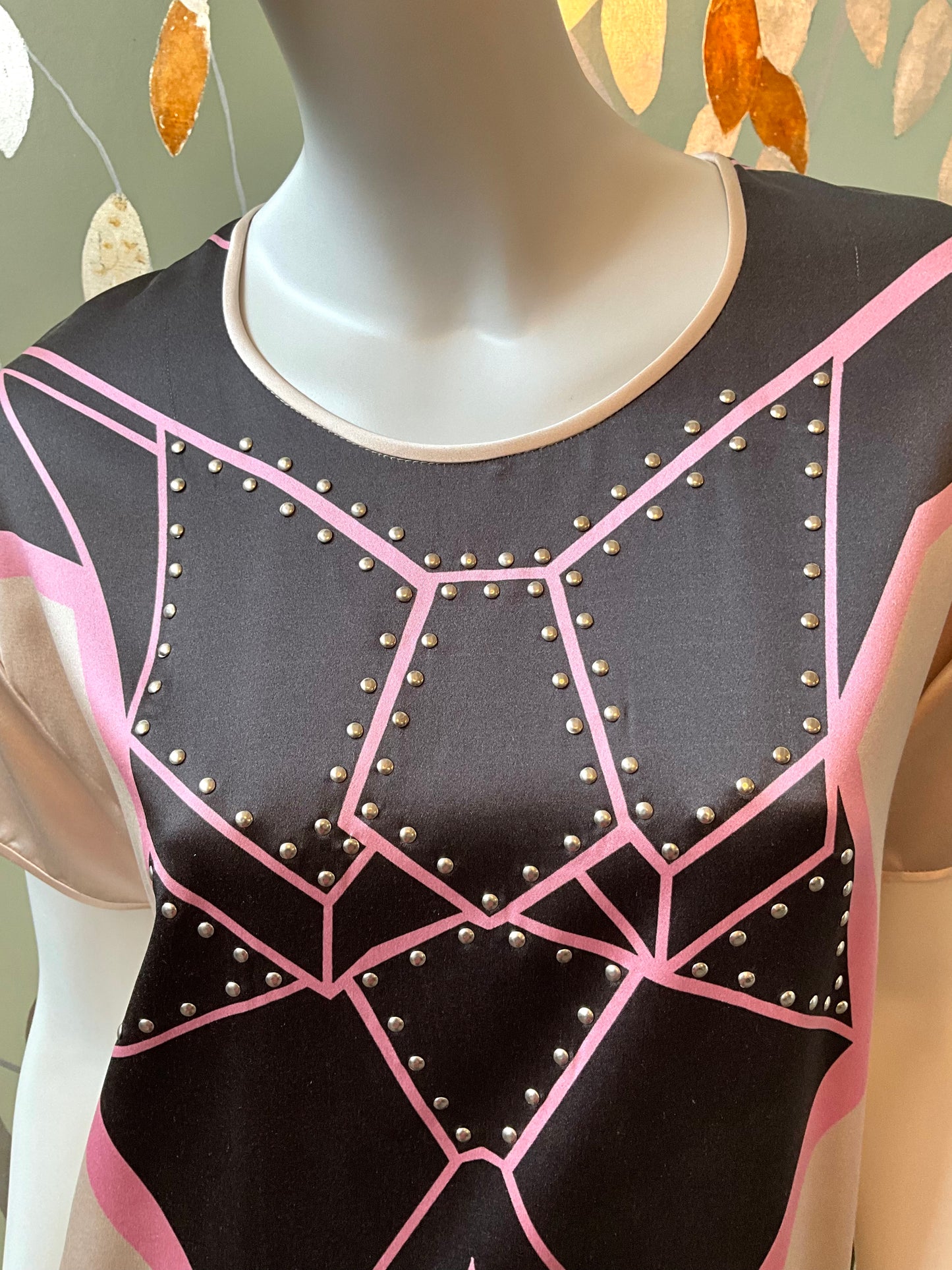 Mannequin wearing a black and pink top with geometric design and stud details.