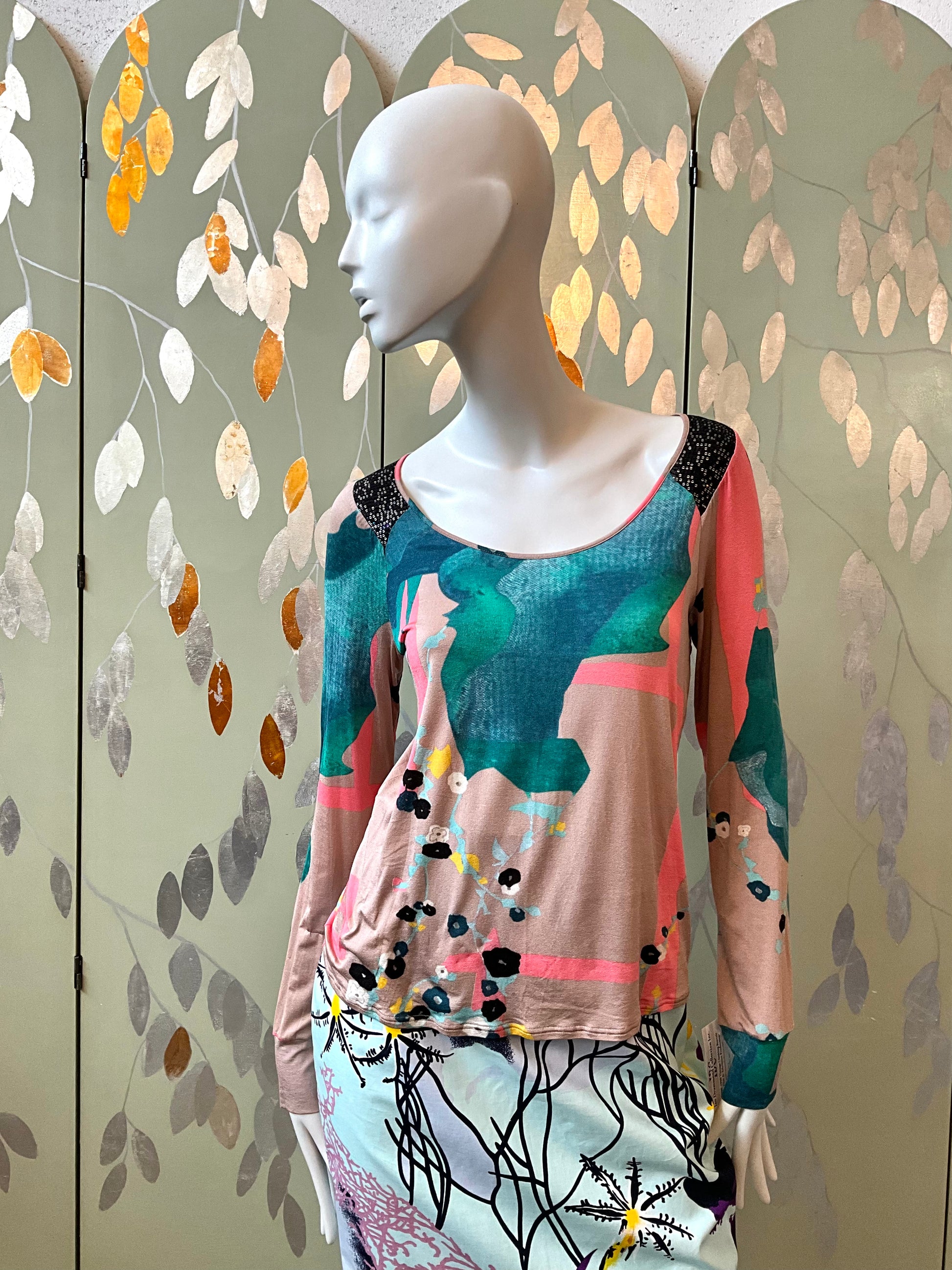 Mannequin wearing a colorful top with a decorative screen in the background