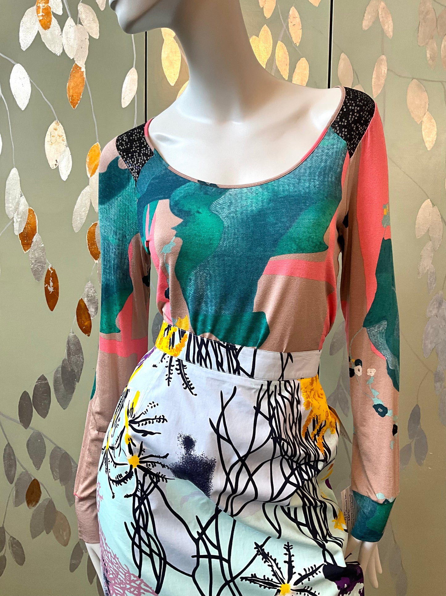 Mannequin wearing a colorful dress with abstract patterns against a leafy background