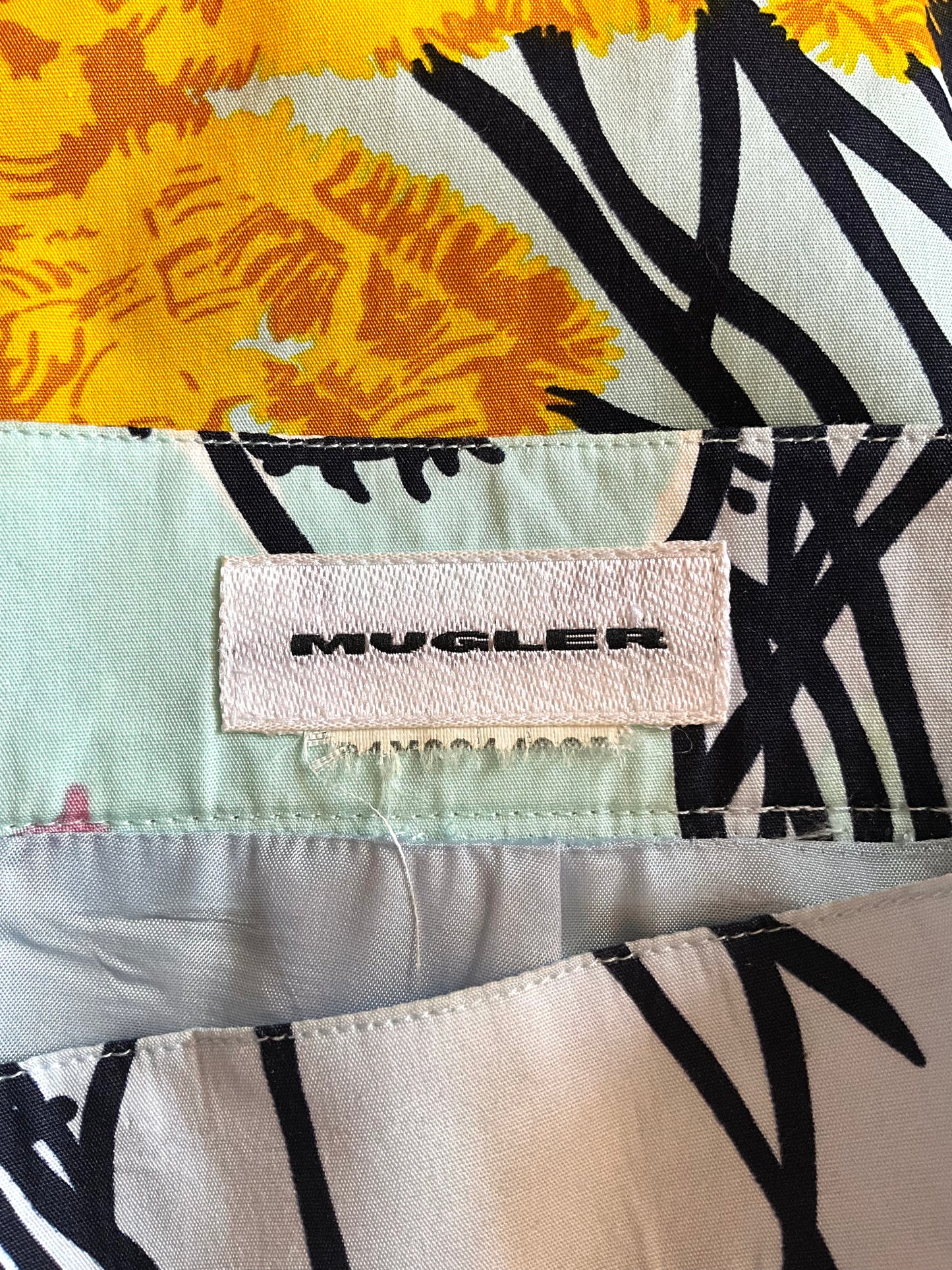 Mugler label on a patterned fabric background