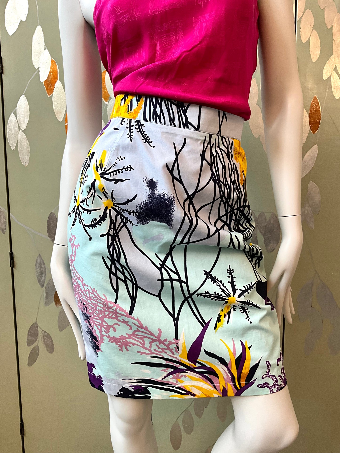 Mannequin wearing a colorful skirt with abstract design against a neutral background