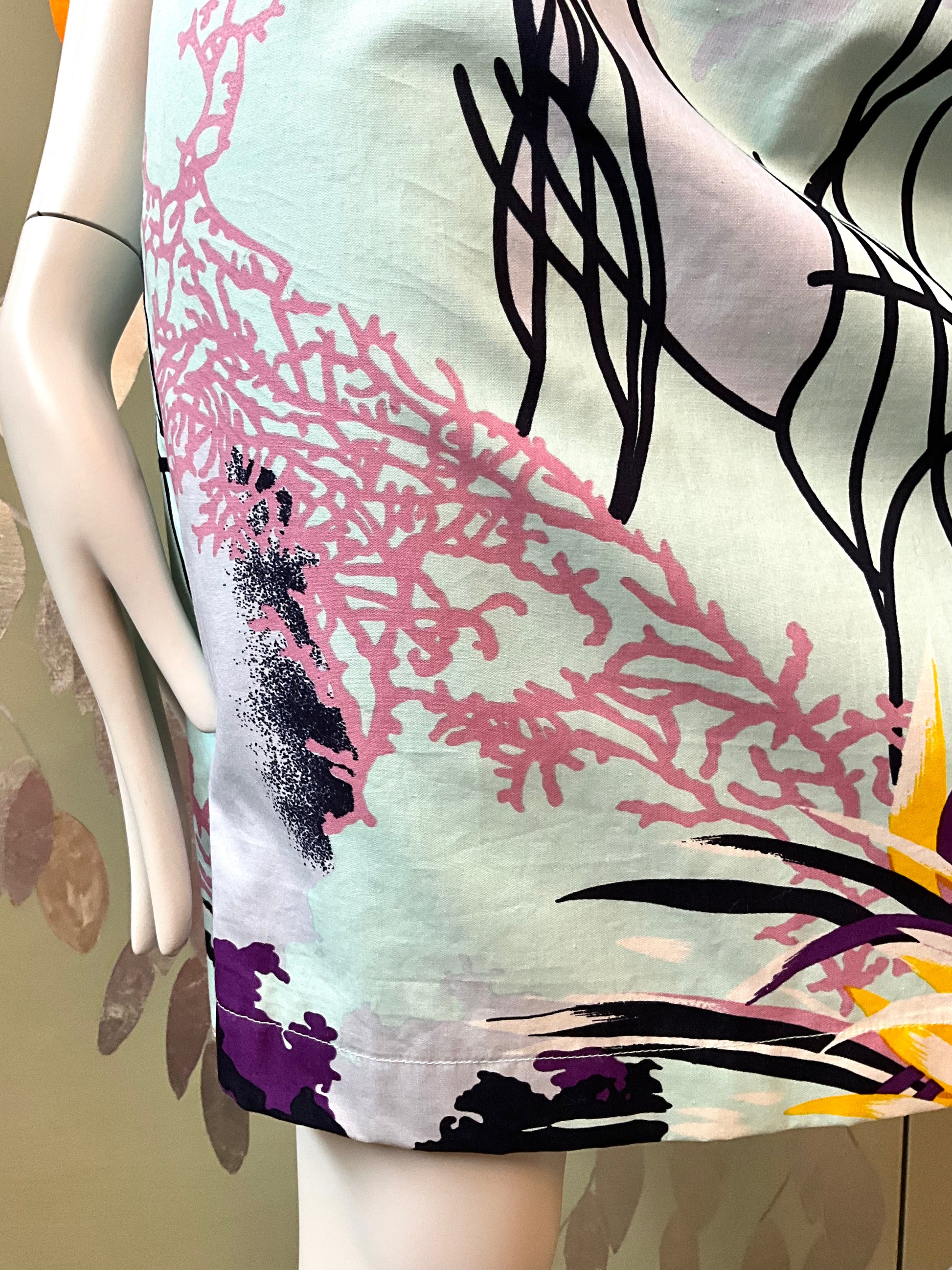 Mannequin wearing a dress with abstract floral design in pink, black, and purple on a neutral background