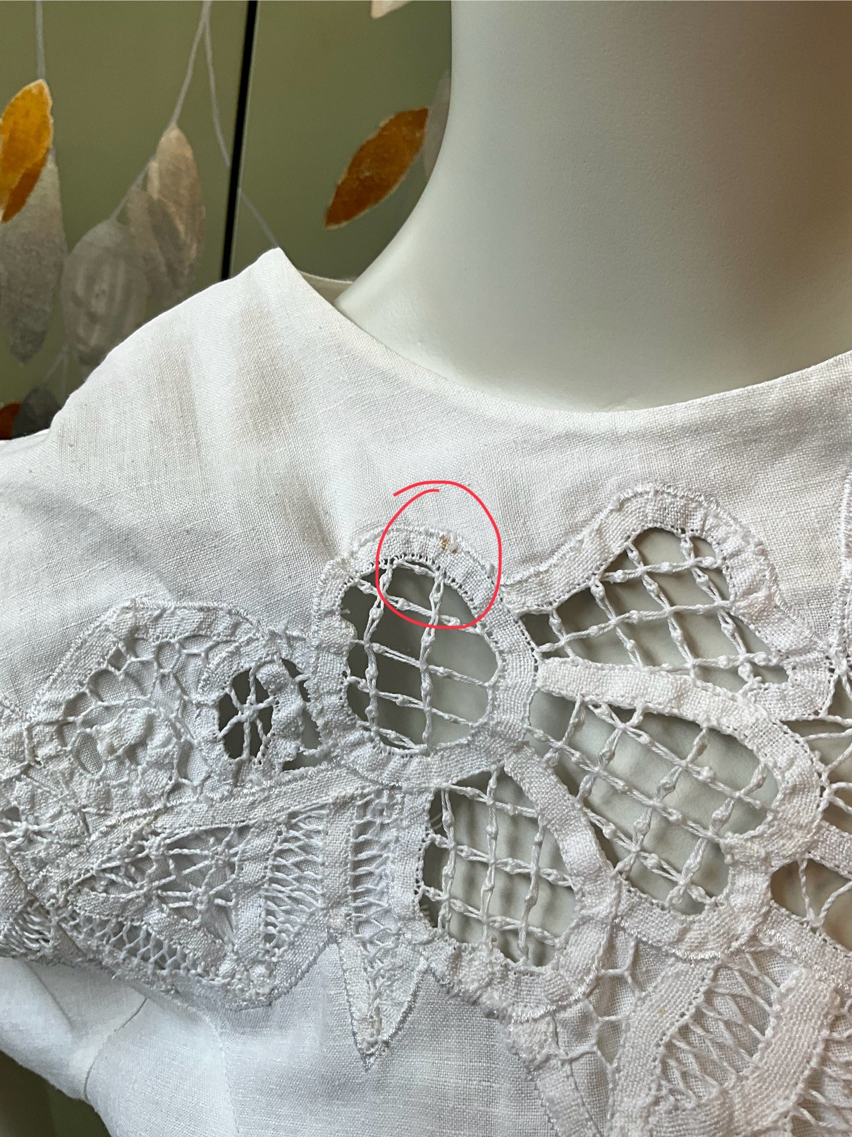 White lace garment on a mannequin with a red circle highlighting a defect.