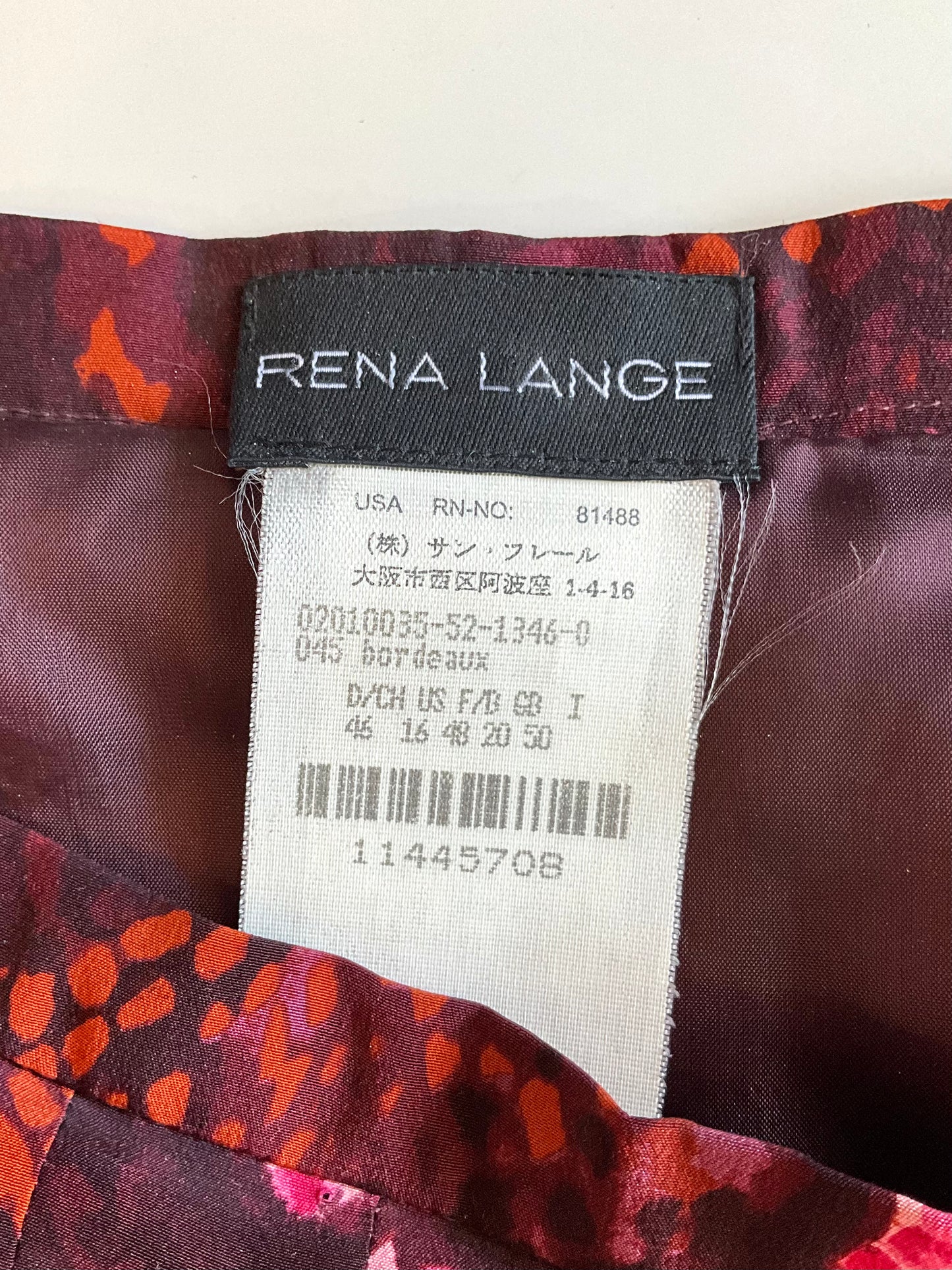 Close-up of a Rena Lange label on a garment with a patterned background.