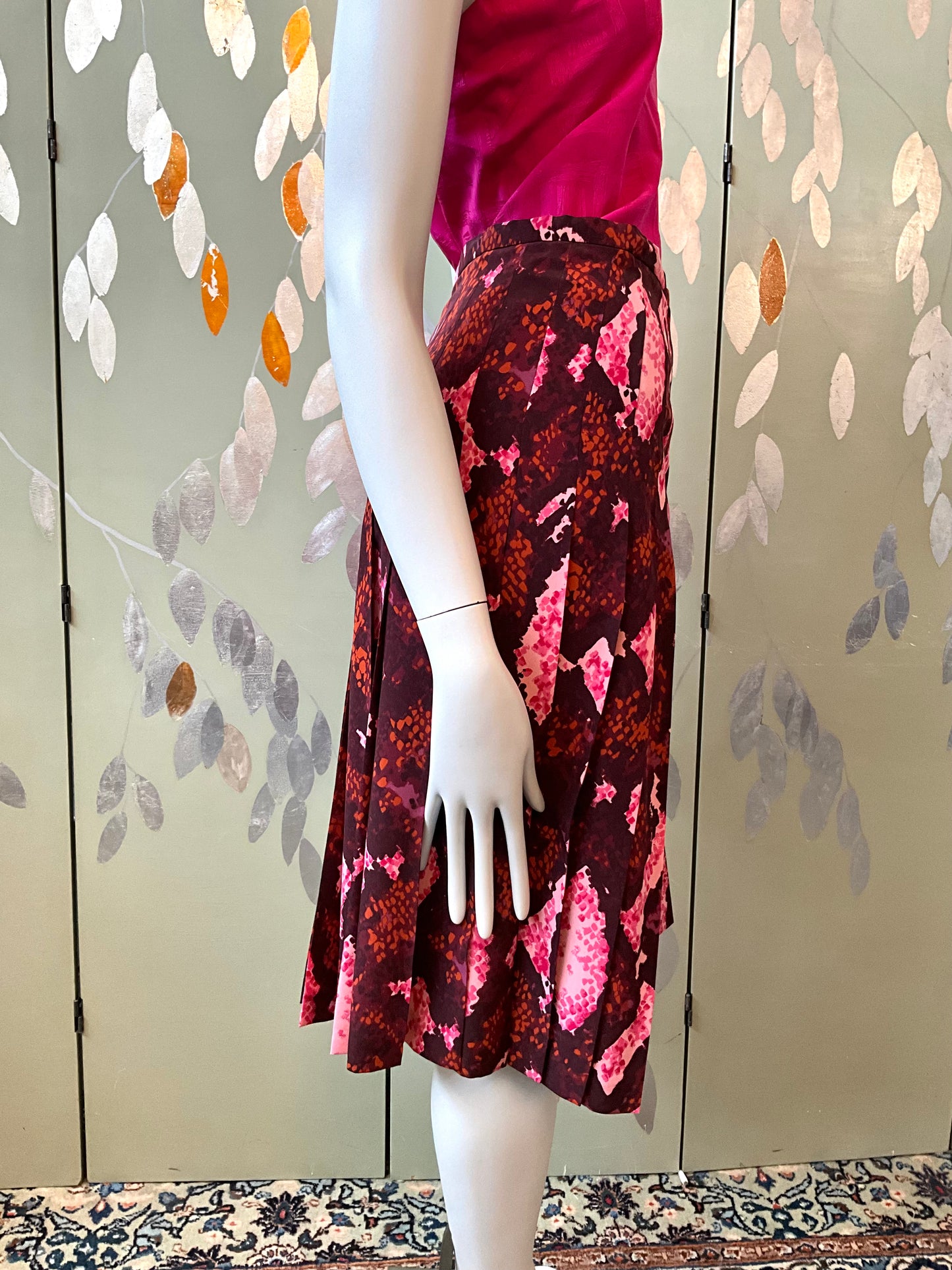 Mannequin wearing a floral skirt with a pink top against a decorative wall.
