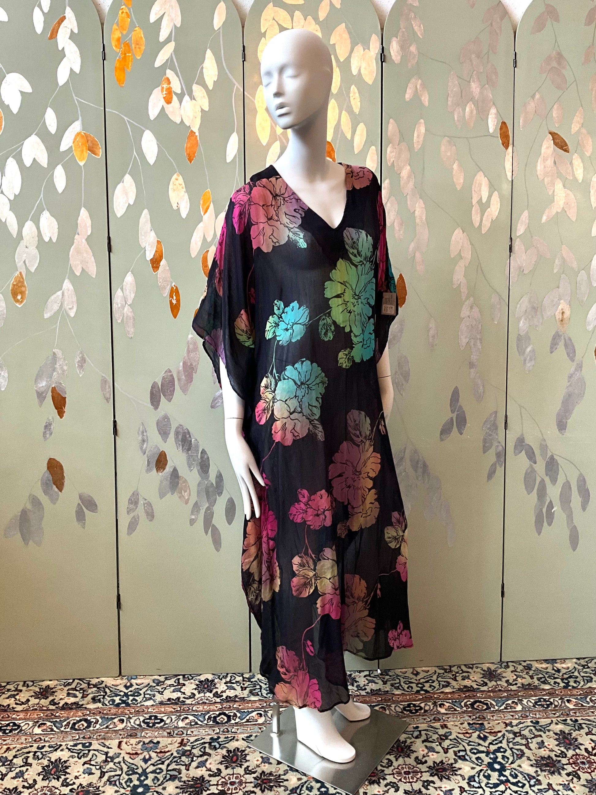 Mannequin wearing a black floral dress in front of a decorative screen.
