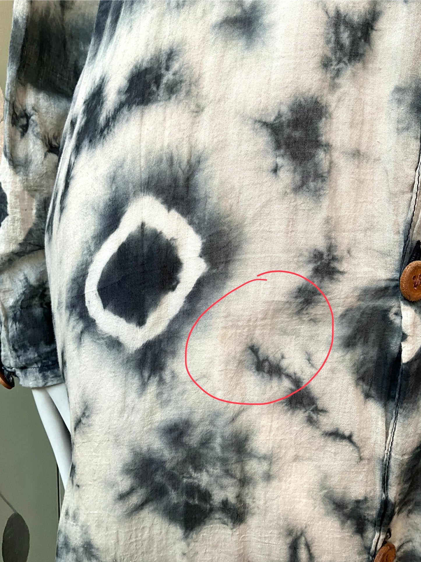 Close-up of a tie-dye shirt and a red circle highlighting a defect.