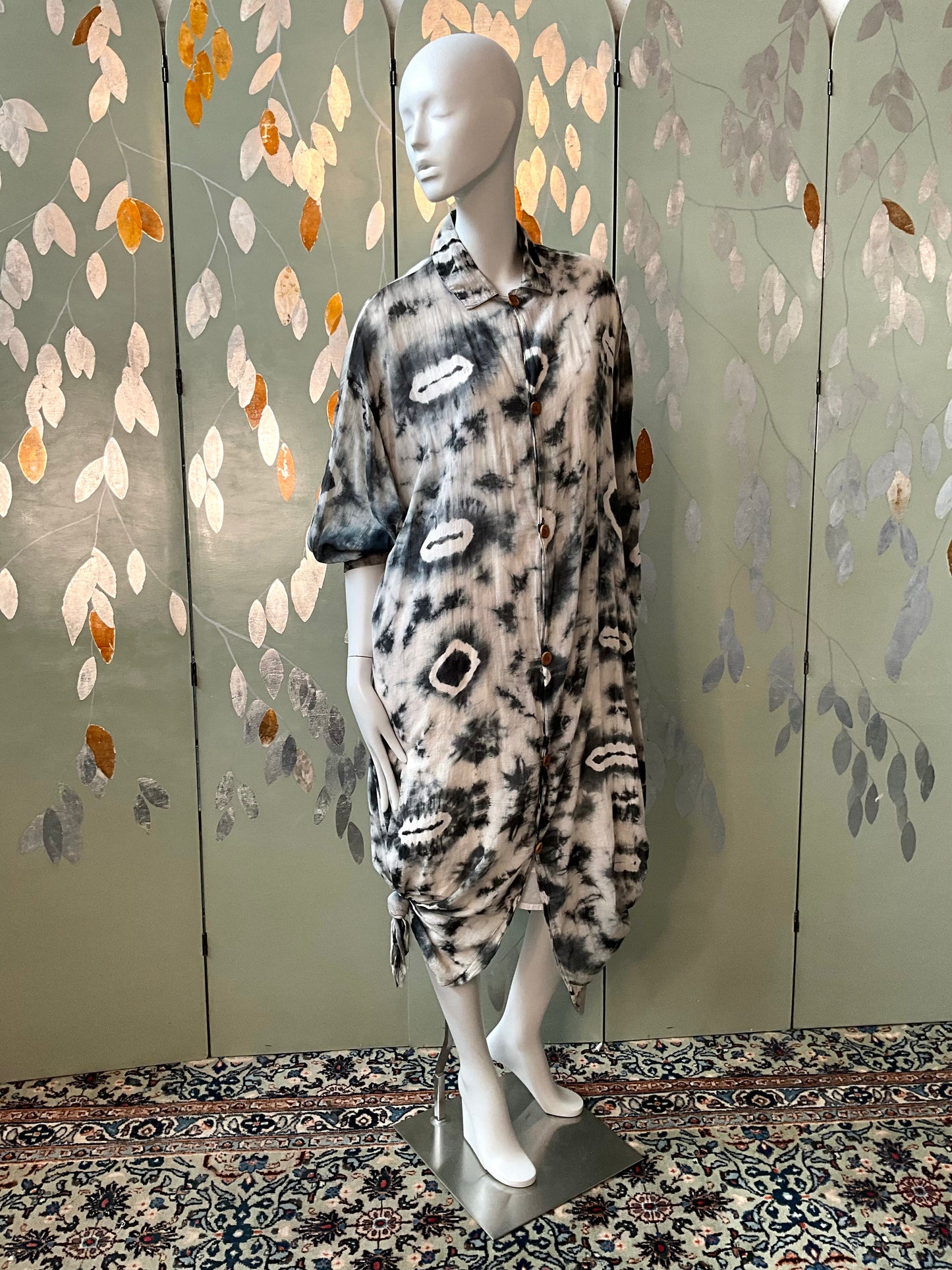 Mannequin wearing a patterned outfit against a decorative wall.