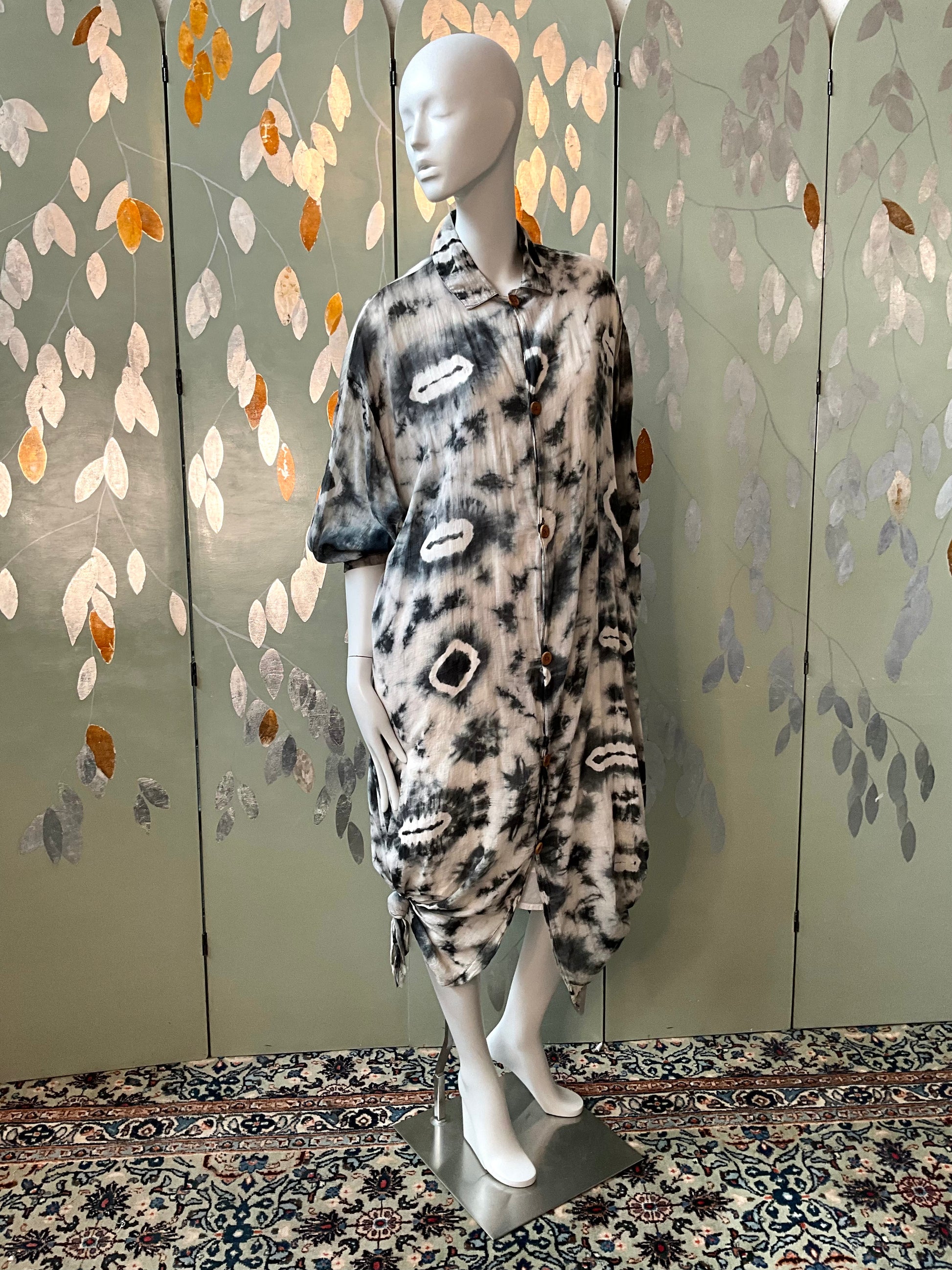 Mannequin wearing a patterned outfit against a decorative wall.
