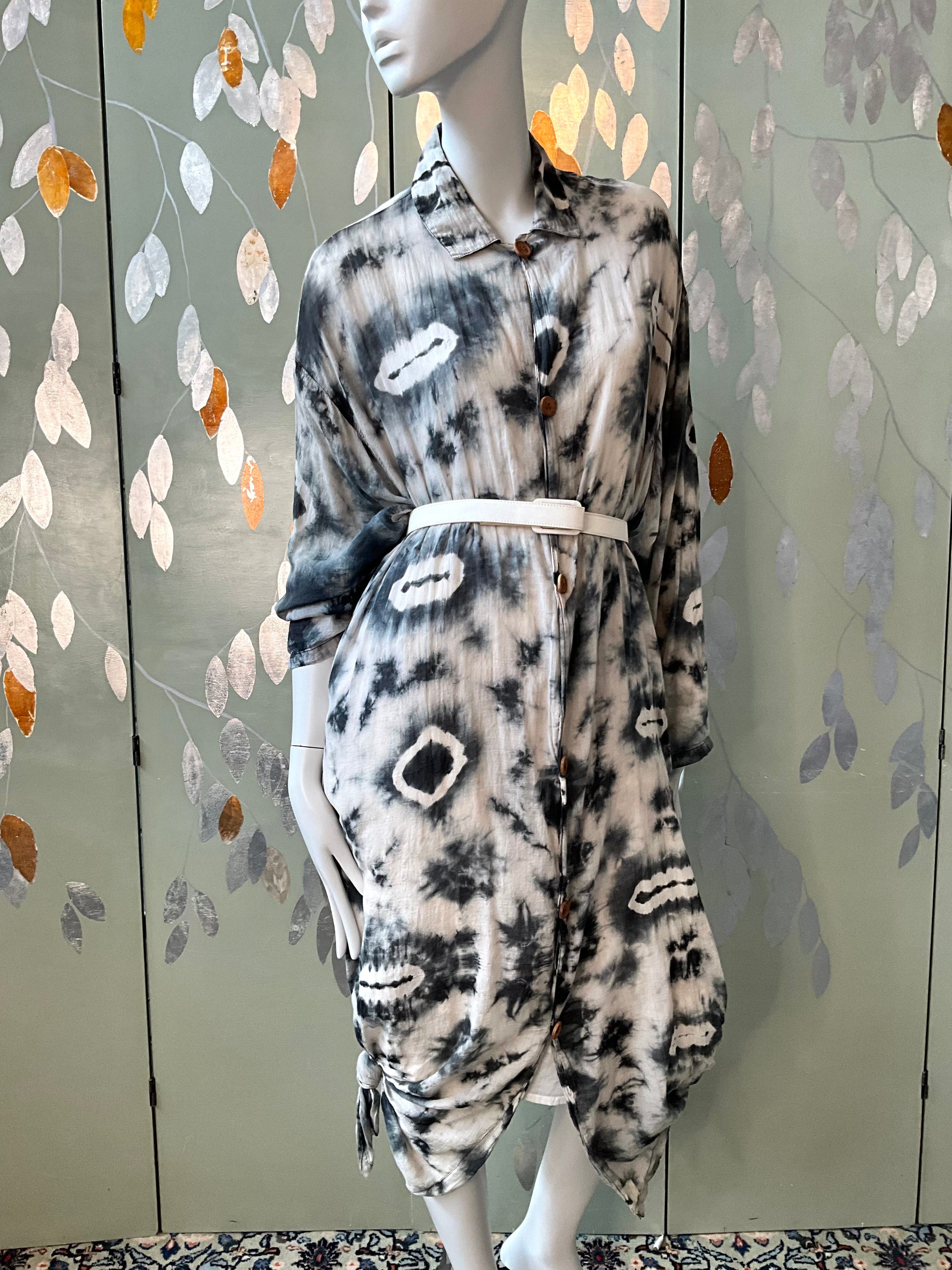 Mannequin wearing a patterned outfit against a decorative wall.