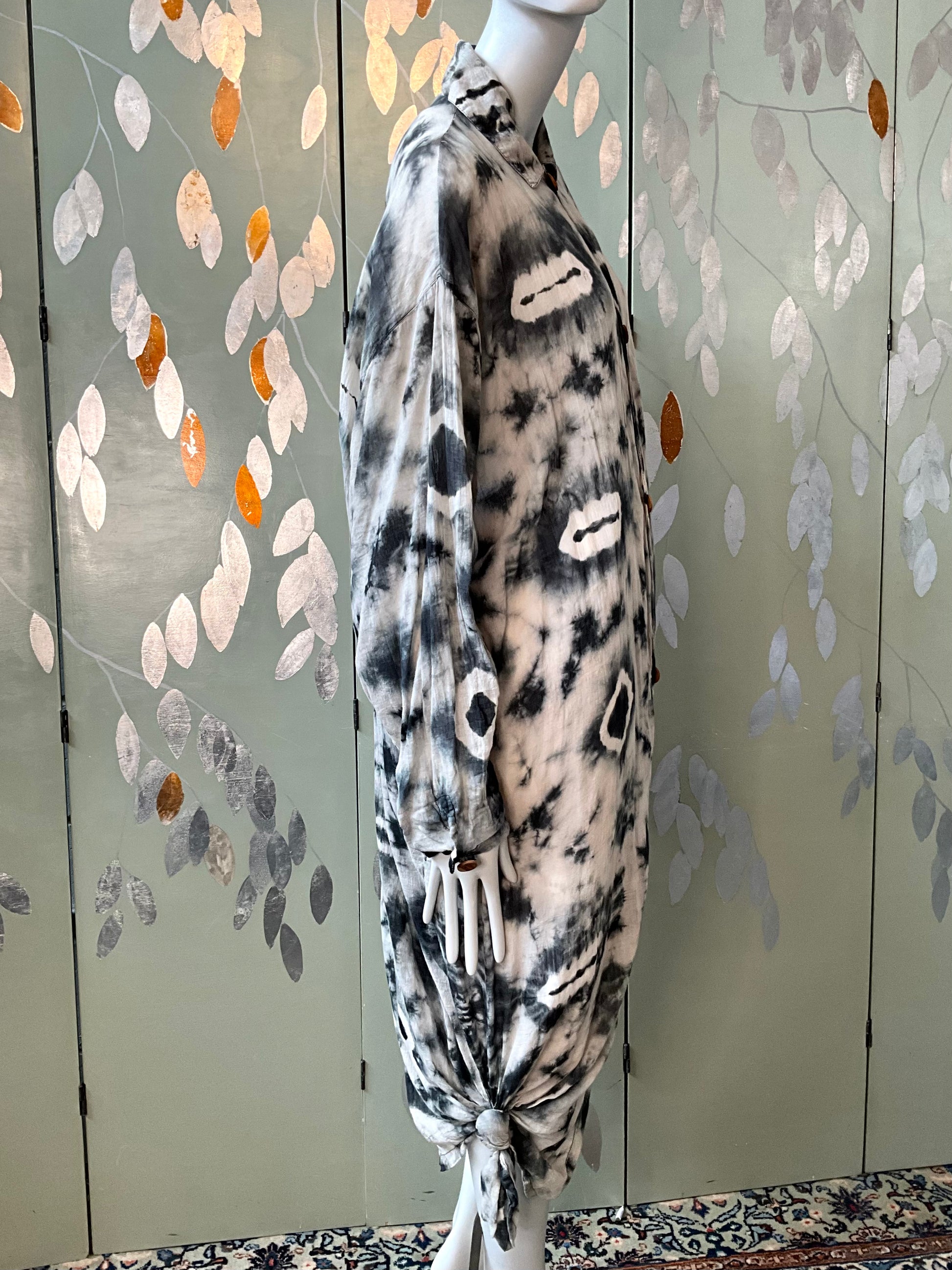 Mannequin wearing a black and white patterned top against a decorative wall.