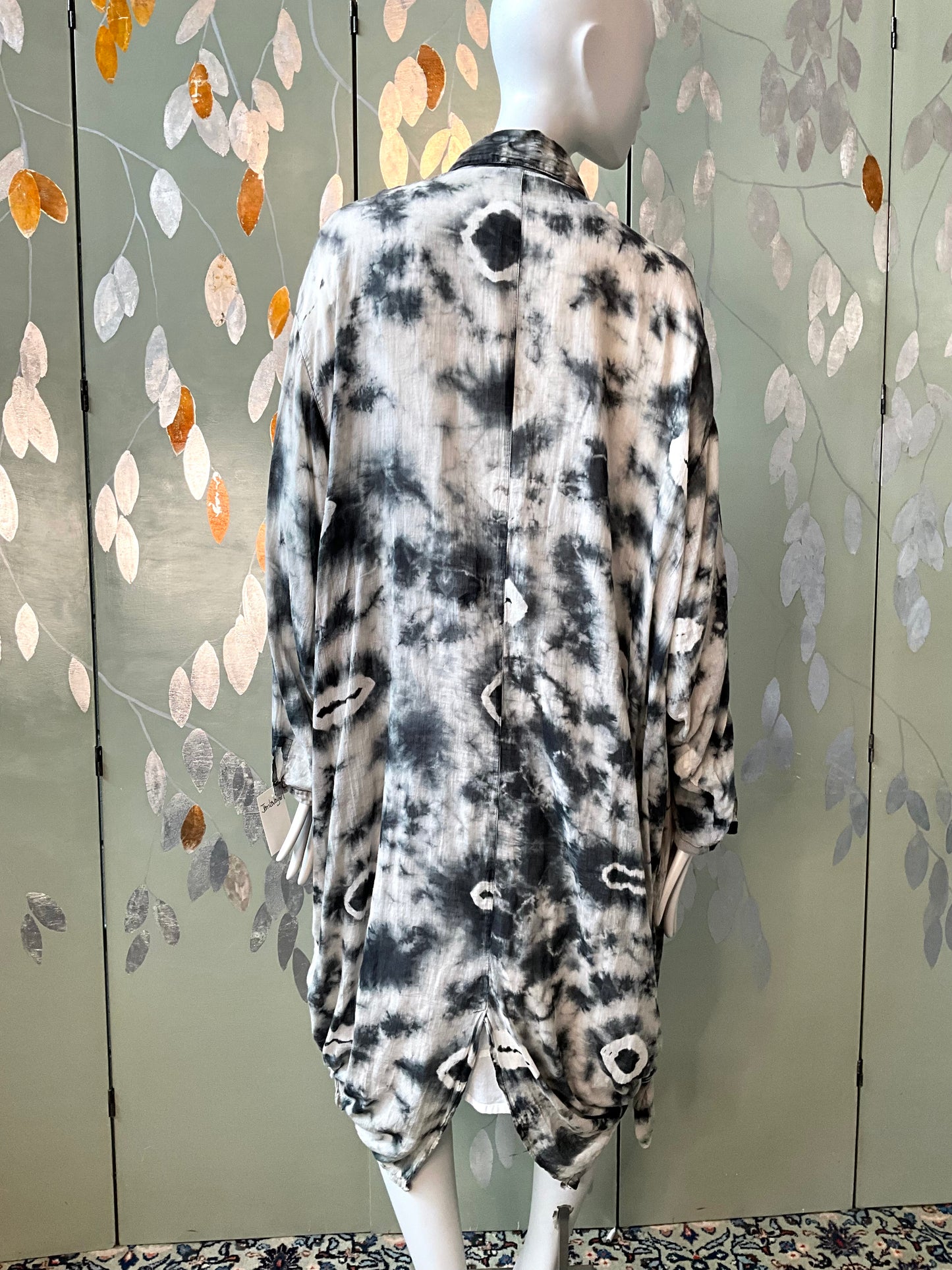 Mannequin wearing a patterned shirt against a decorative wall.