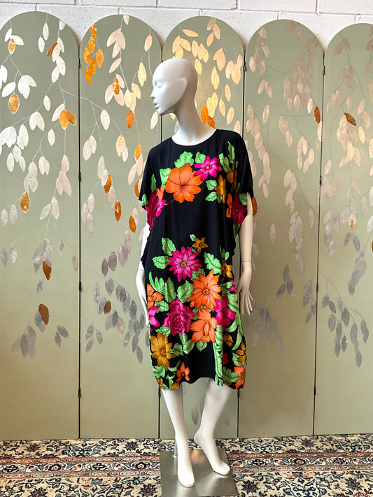Mannequin wearing a black dress with colorful floral patterns against a decorative screen.