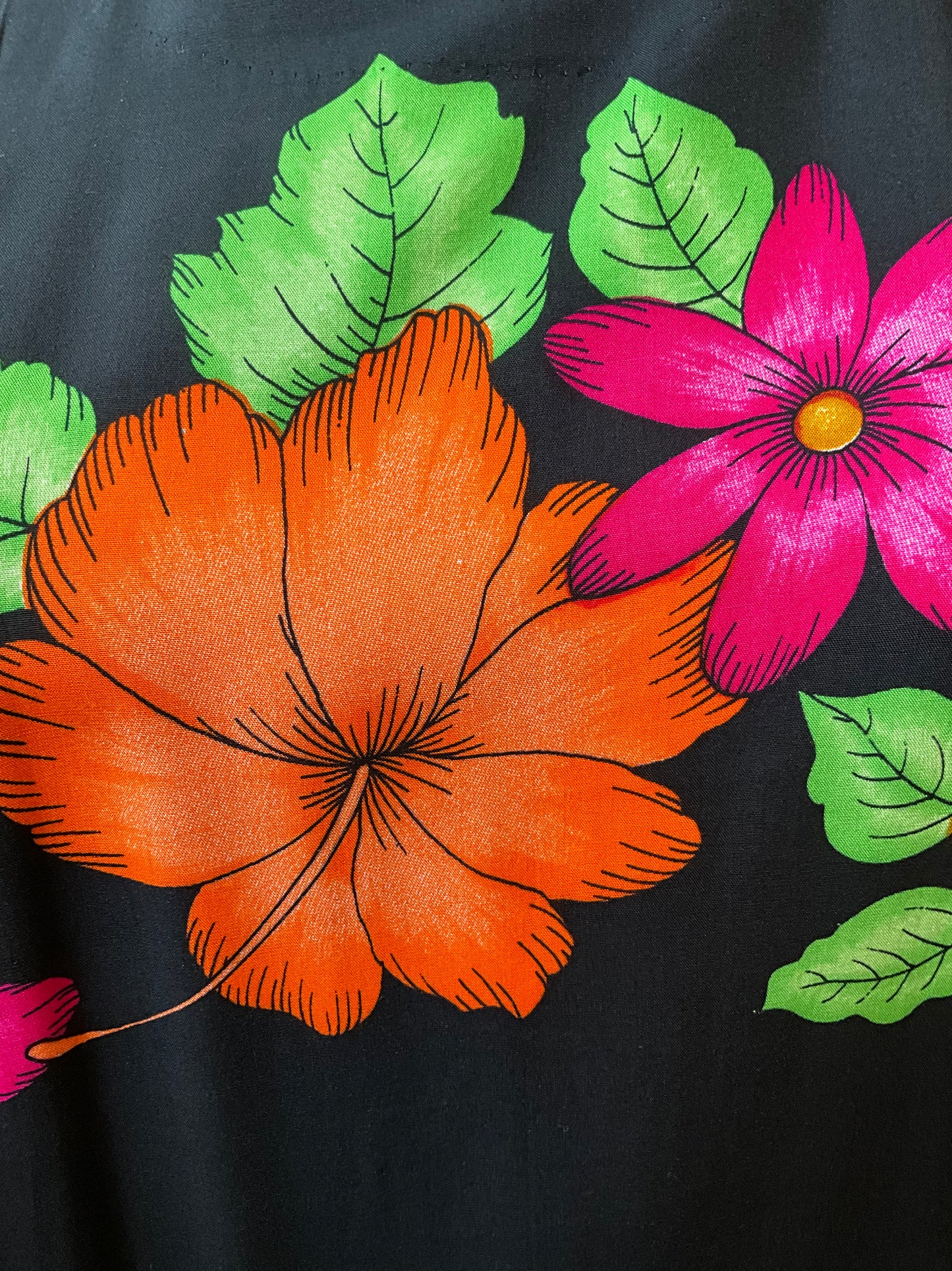 Floral design with orange flower, pink flower, and green leaves on a black background