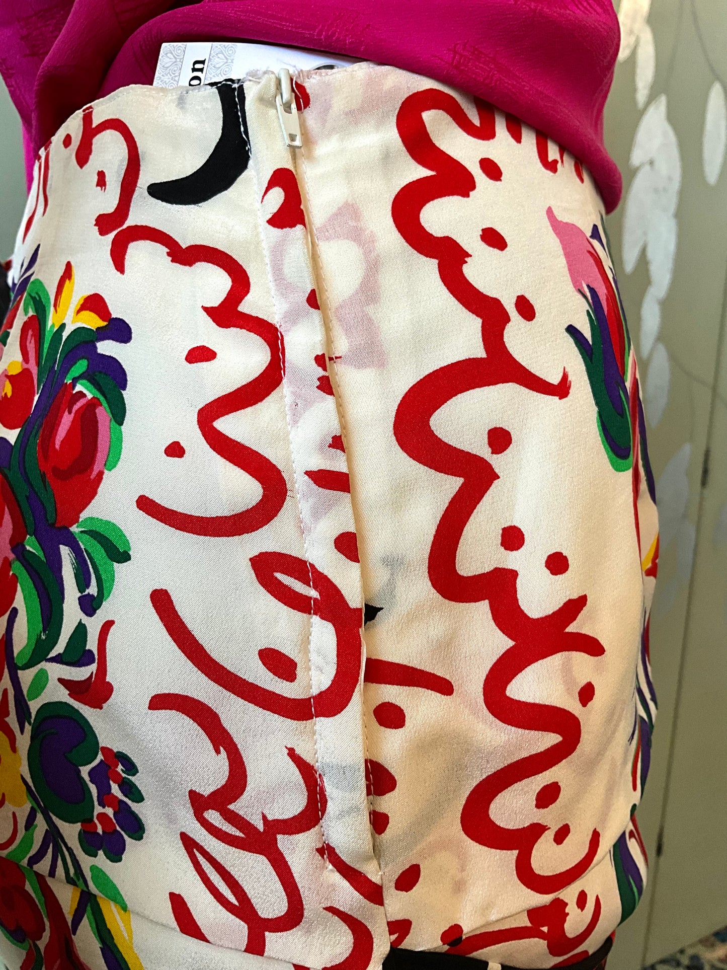 Colorful skirt with red abstract patterns and floral designs on a white background.