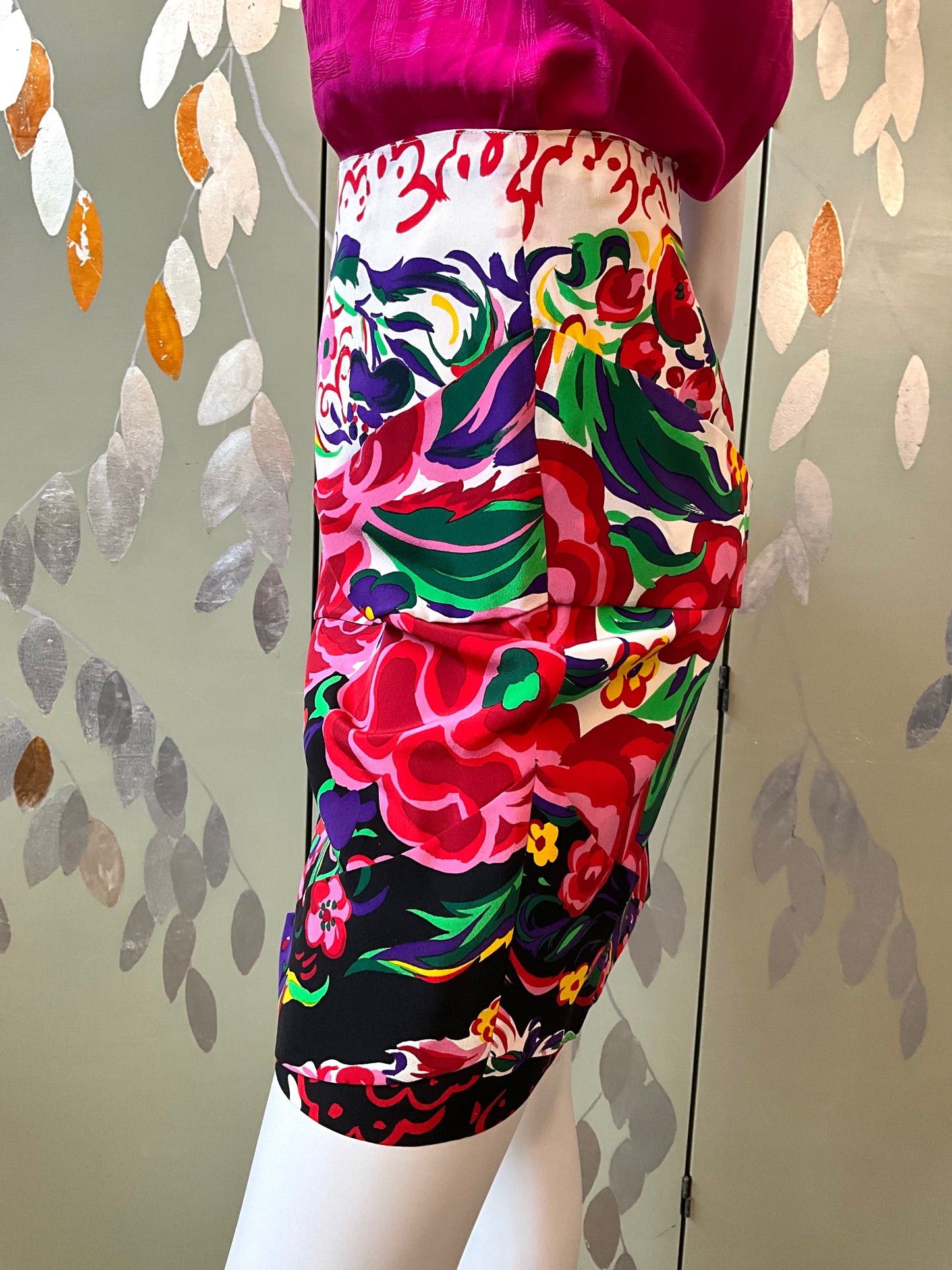 Colorful floral-patterned skirt on a mannequin against a patterned wall.
