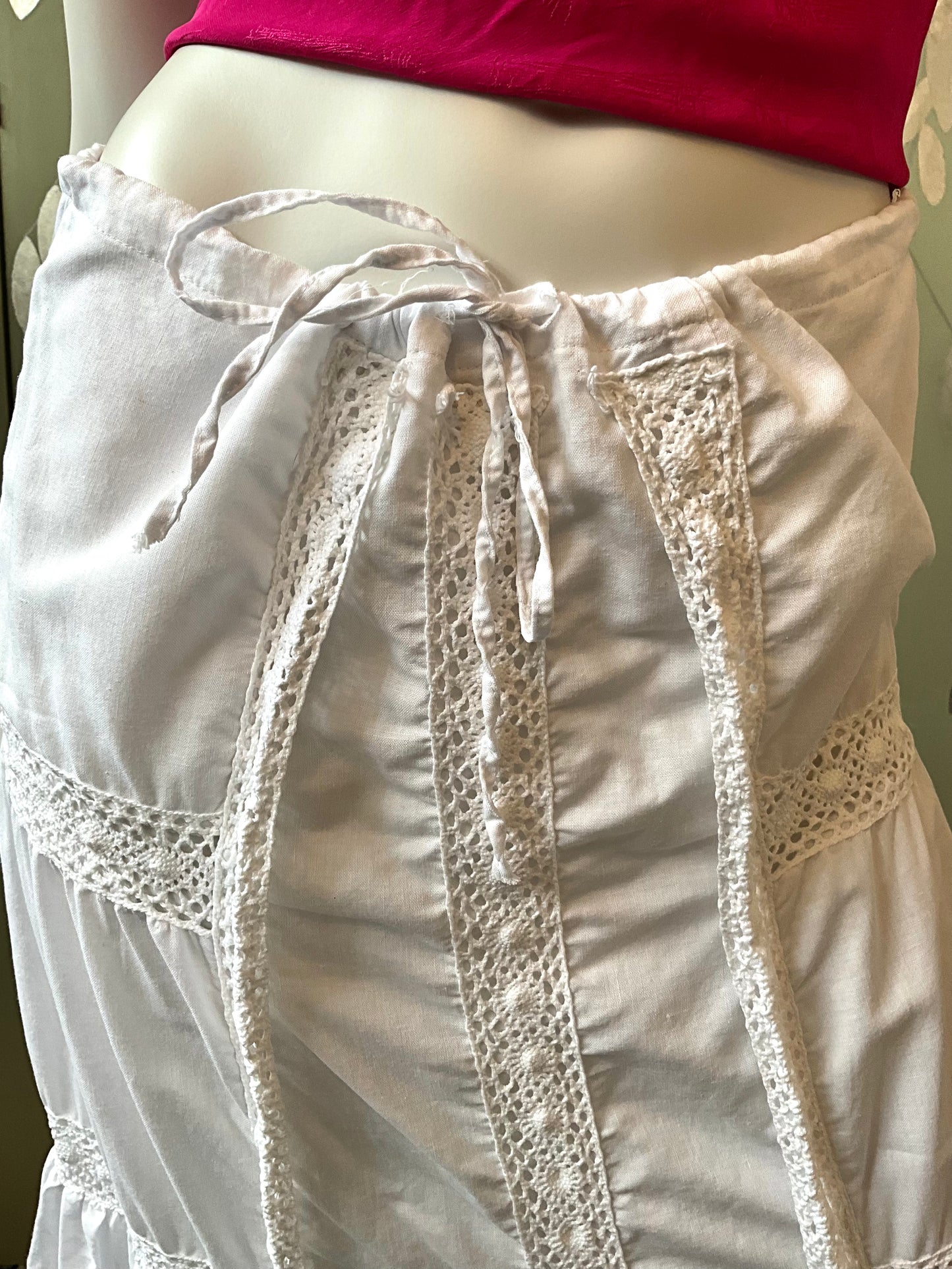 White crochet-trimmed skirt on a mannequin with a pink top.