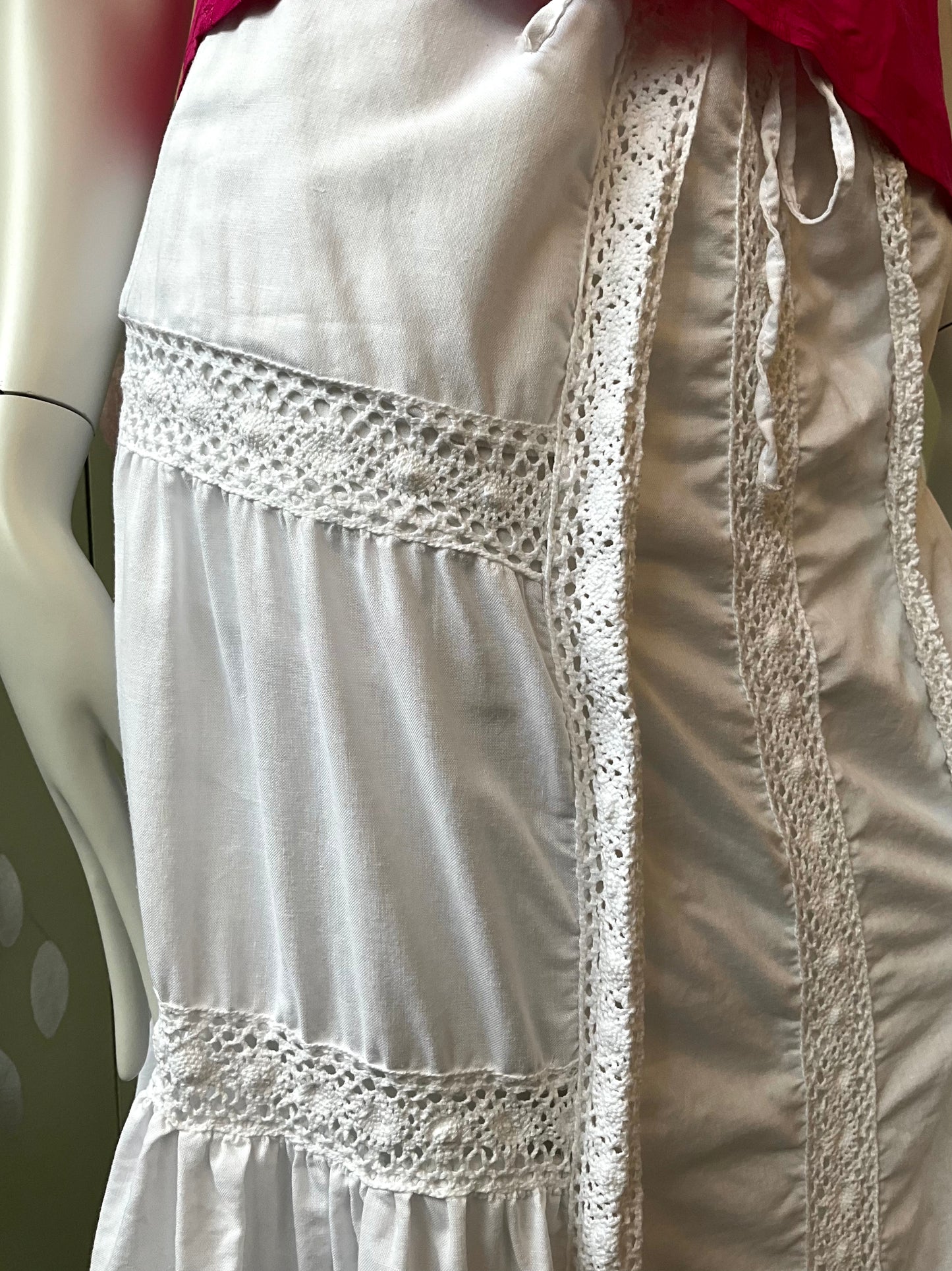 White lace-trimmed dress on a mannequin with a pink top partially visible.