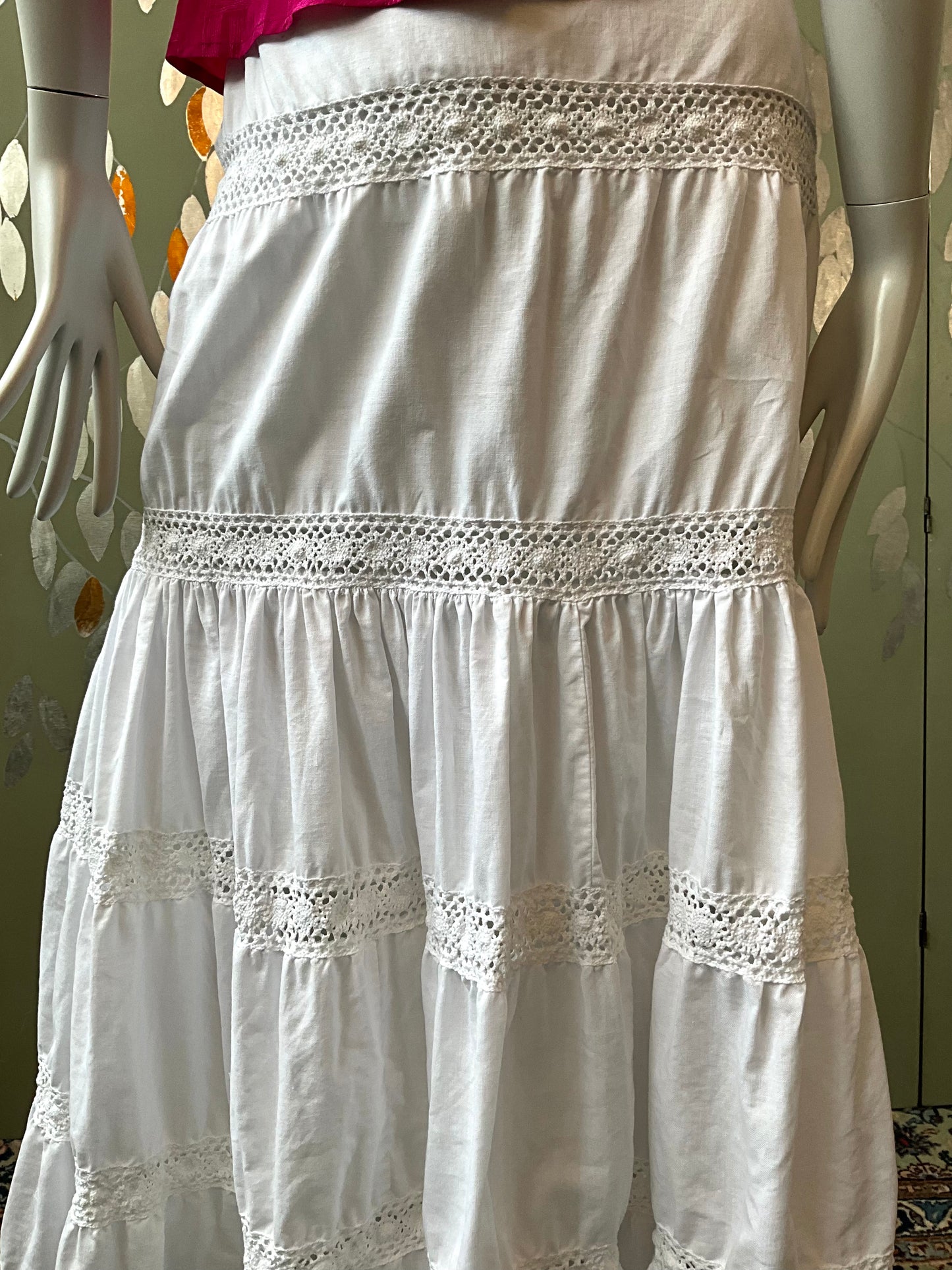 White skirt with lace details on a mannequin against a neutral background