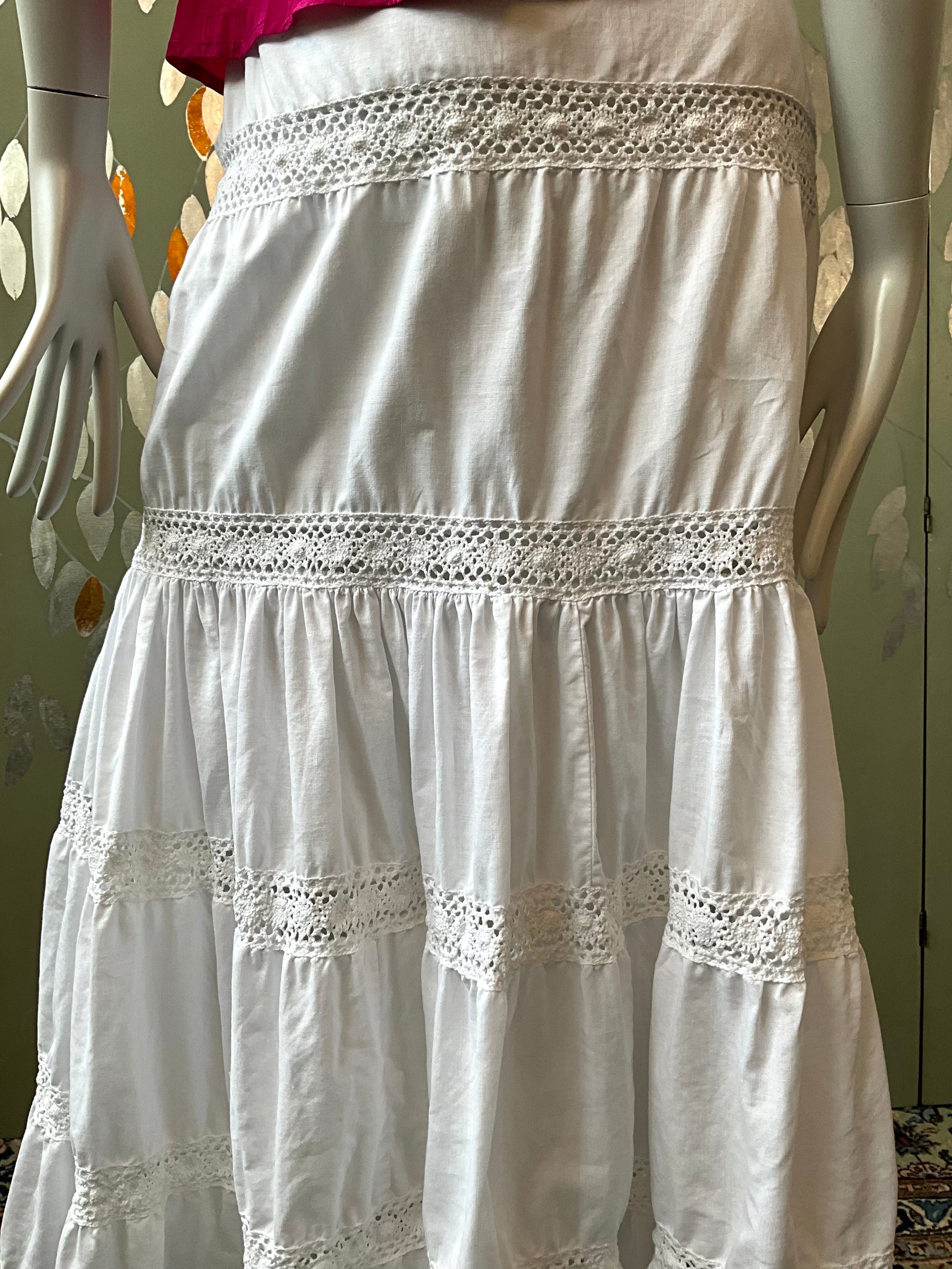 White skirt with lace details on a mannequin against a neutral background