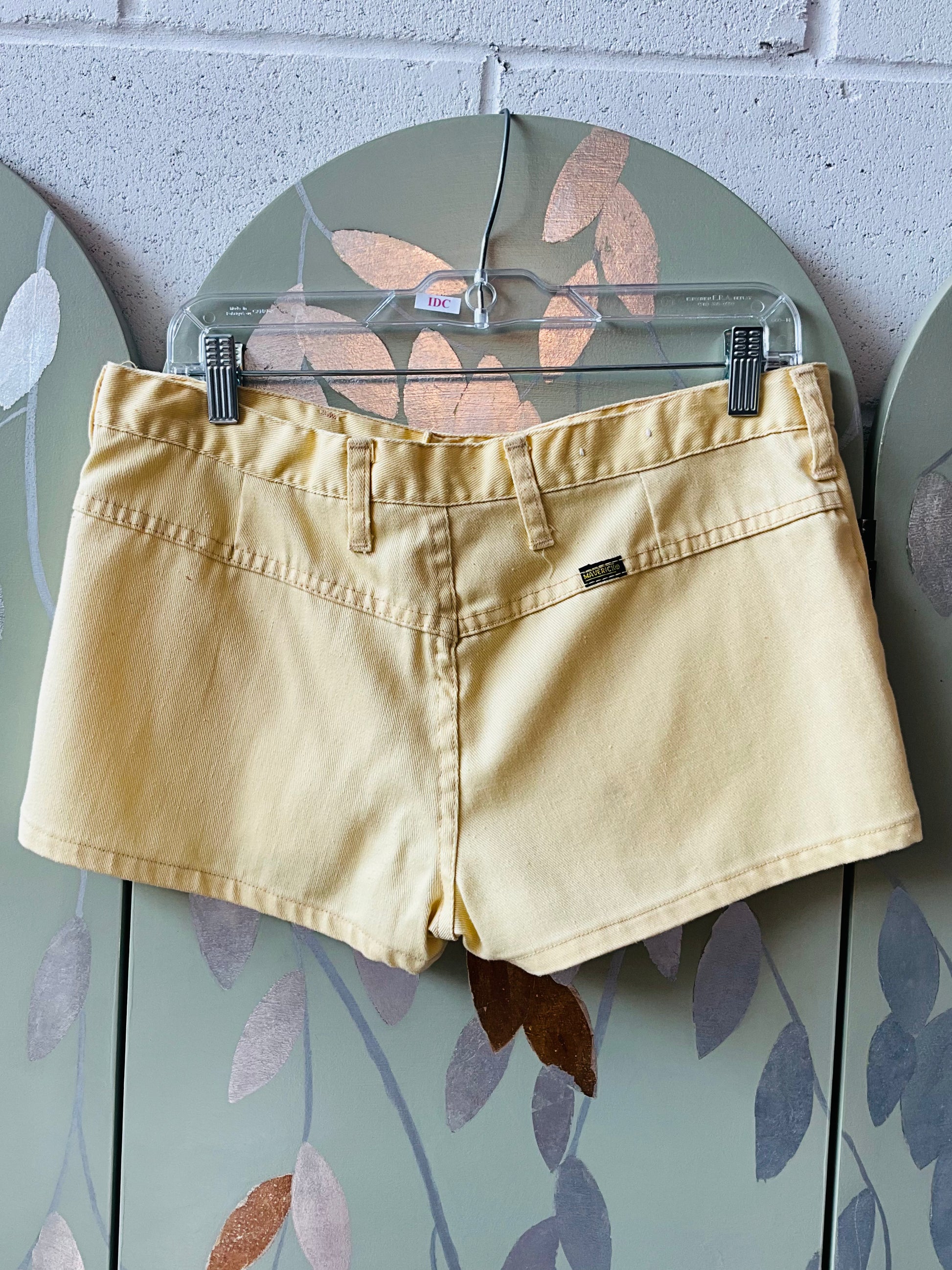 yellow shorts on a hanger against a wall with decorative elements.