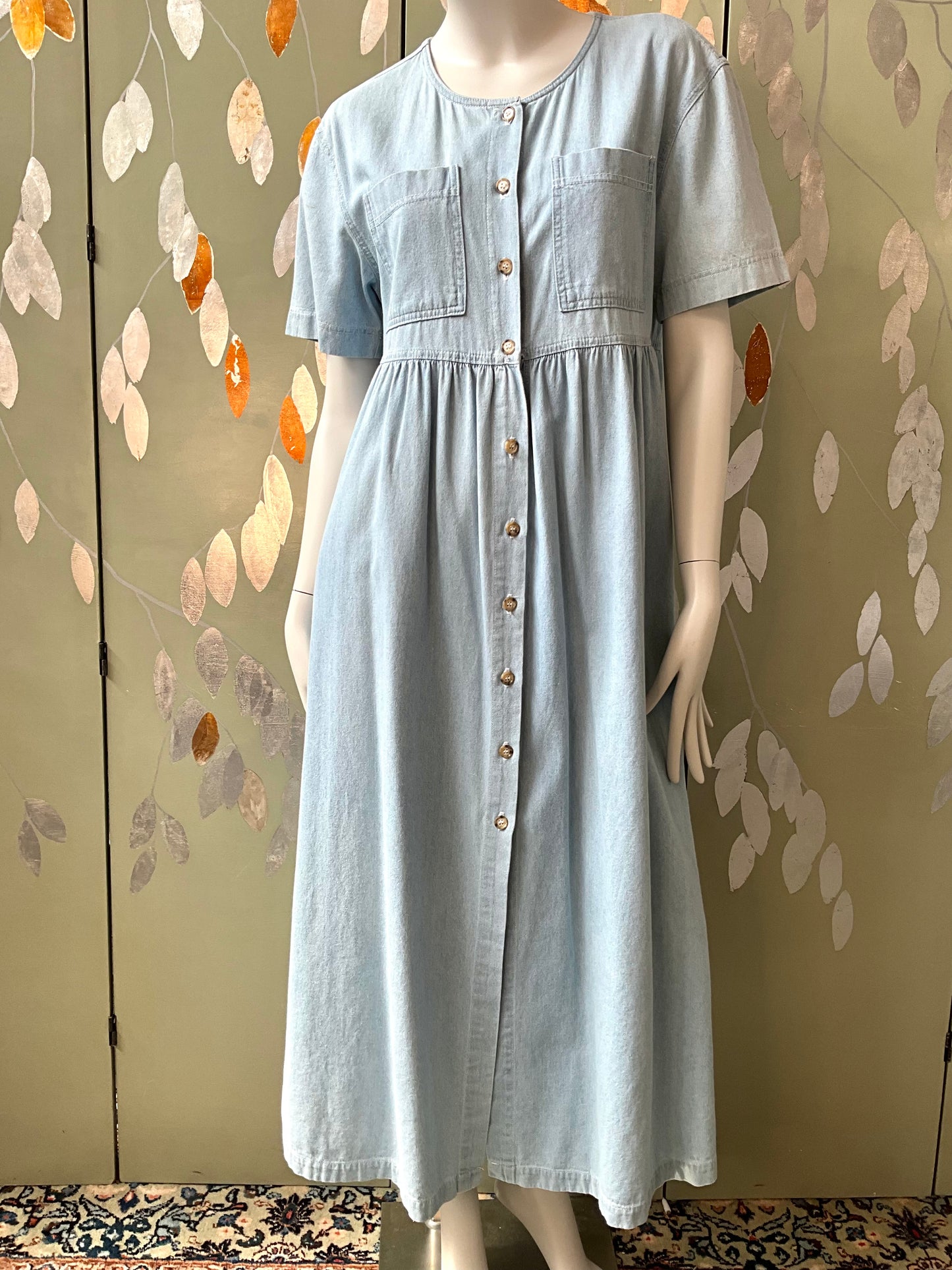 Light blue dress on a mannequin against a decorative wall.
