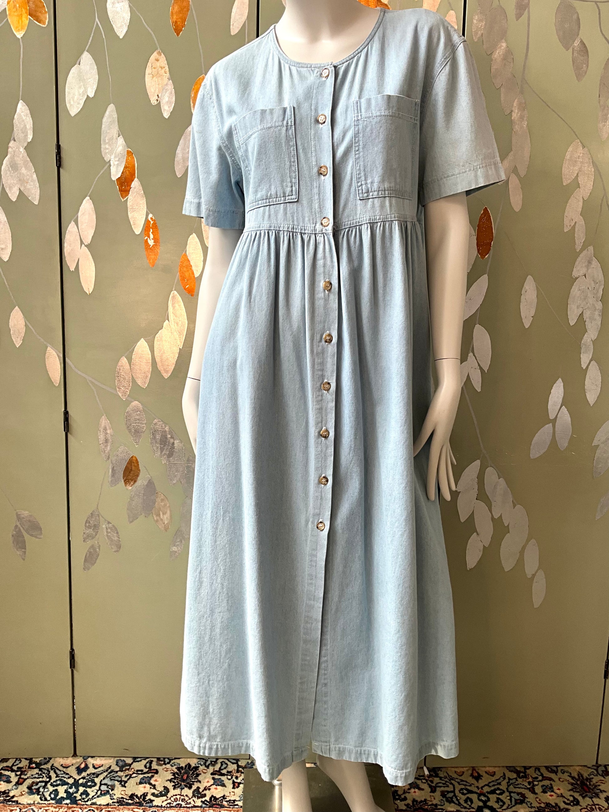 Light blue dress on a mannequin against a decorative wall.