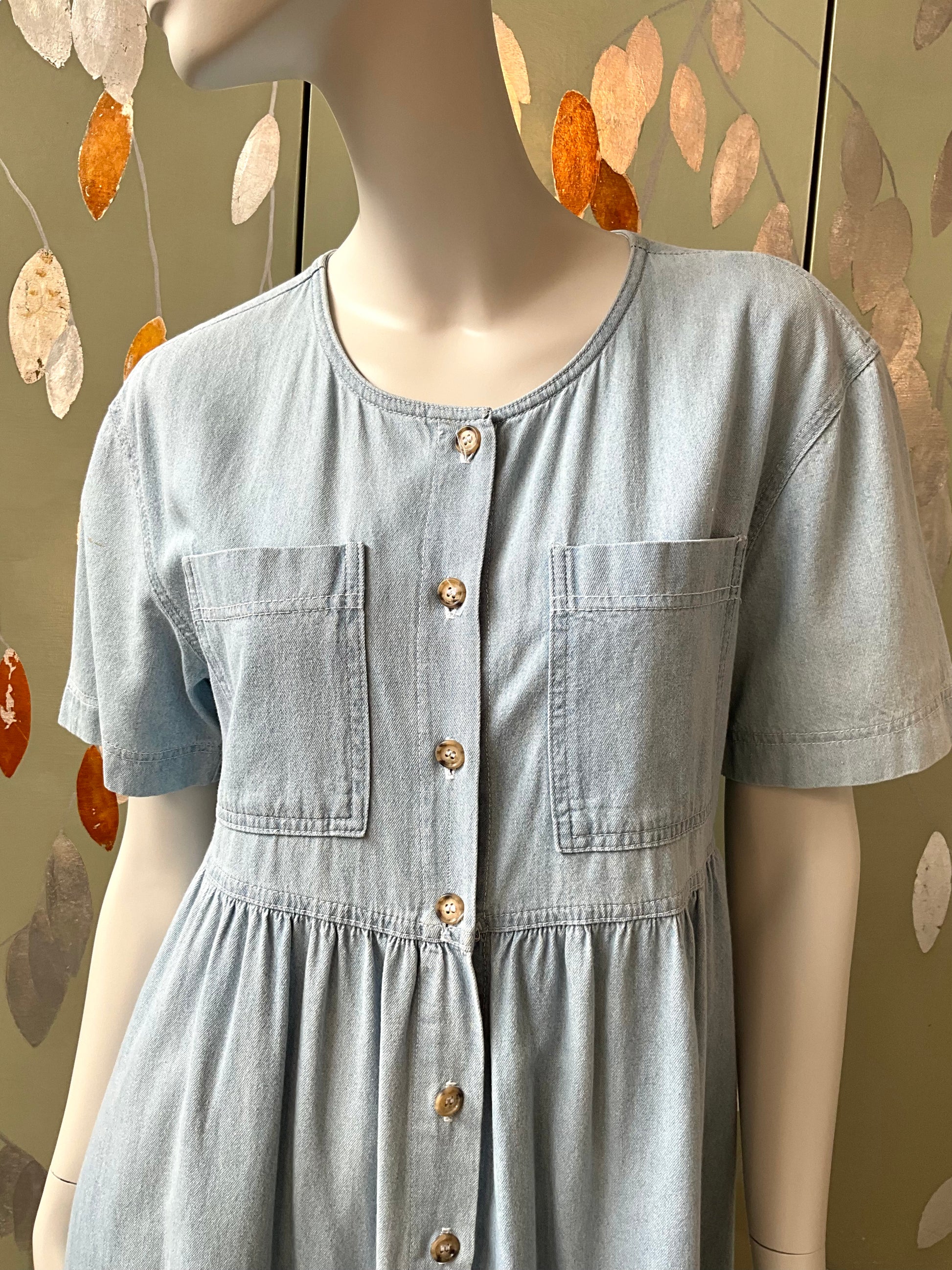 Light blue dress on a mannequin with a decorative leaf background