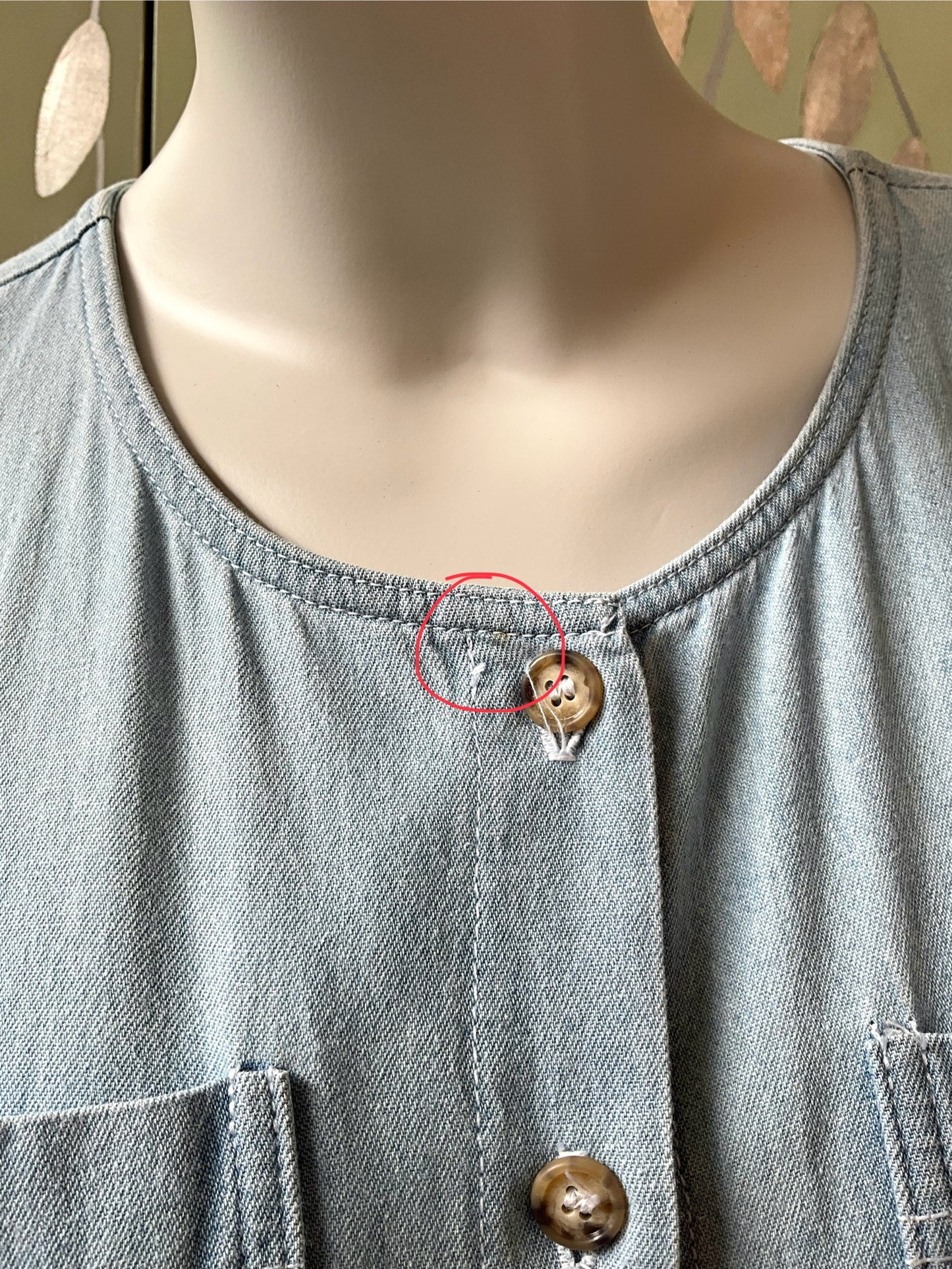 Light blue dress with a button and a red circle highlighting a small defect.