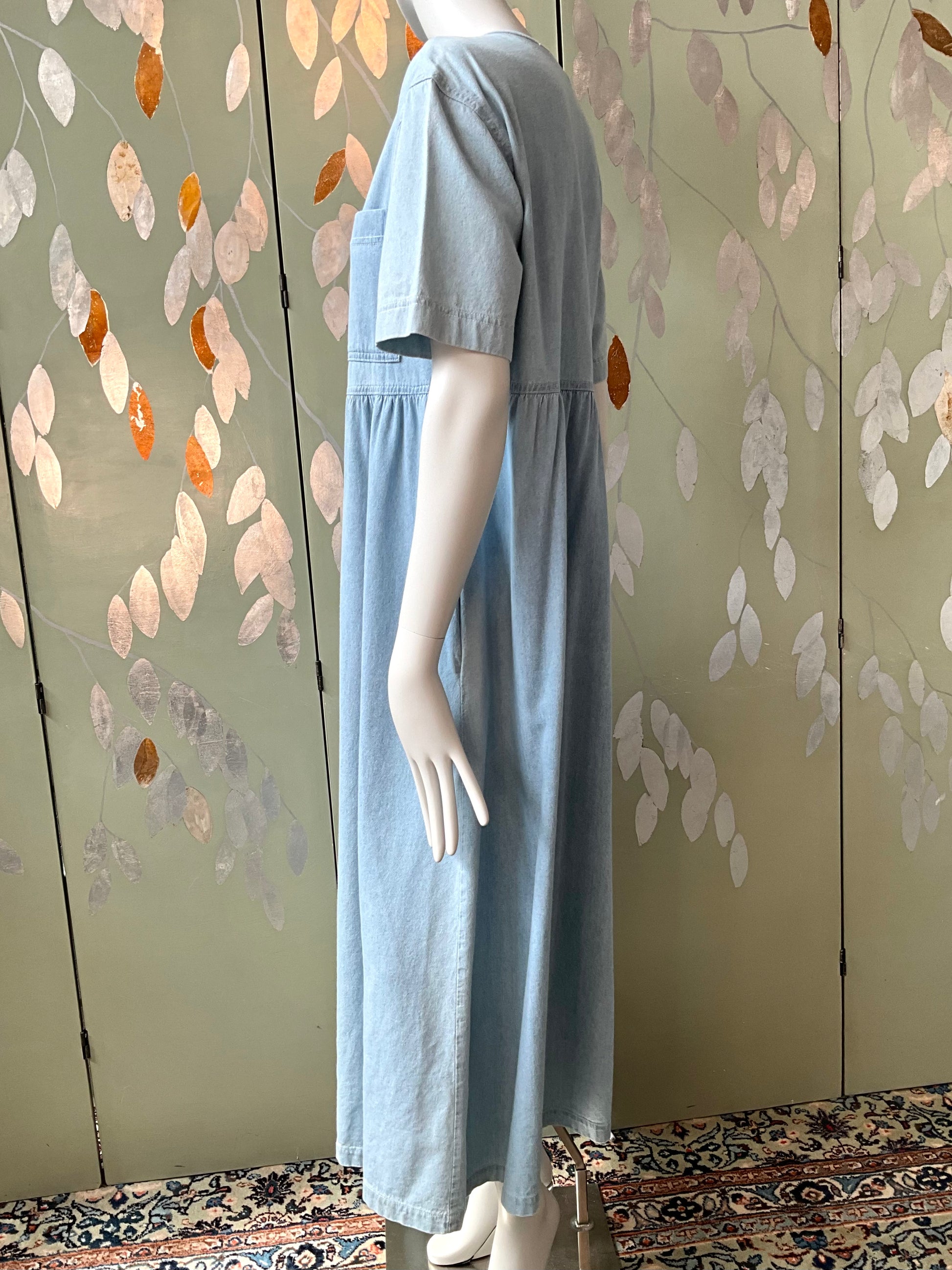 Mannequin wearing a light blue dress against a decorative wall.