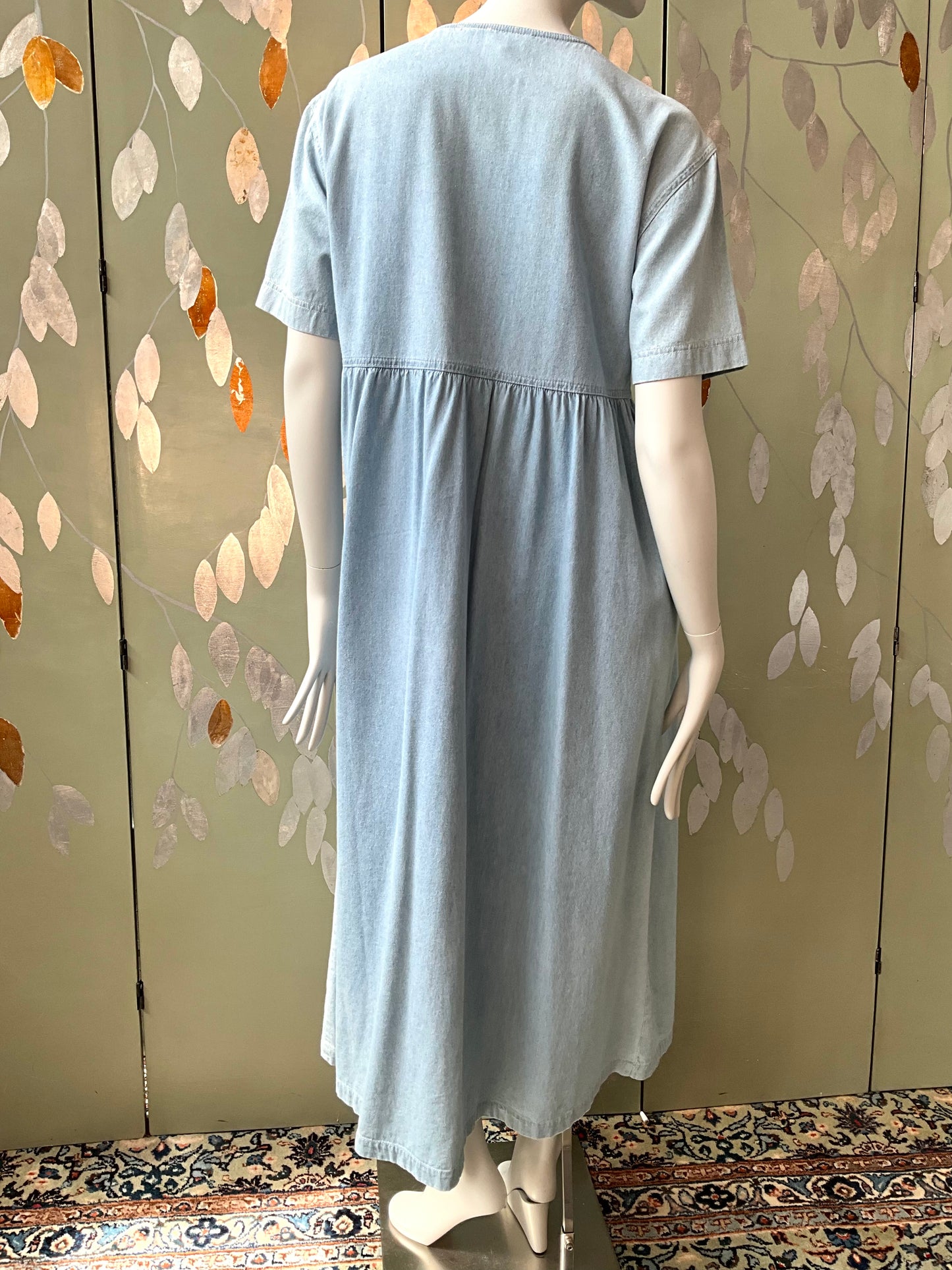 Light blue dress on a mannequin against a decorative wall.