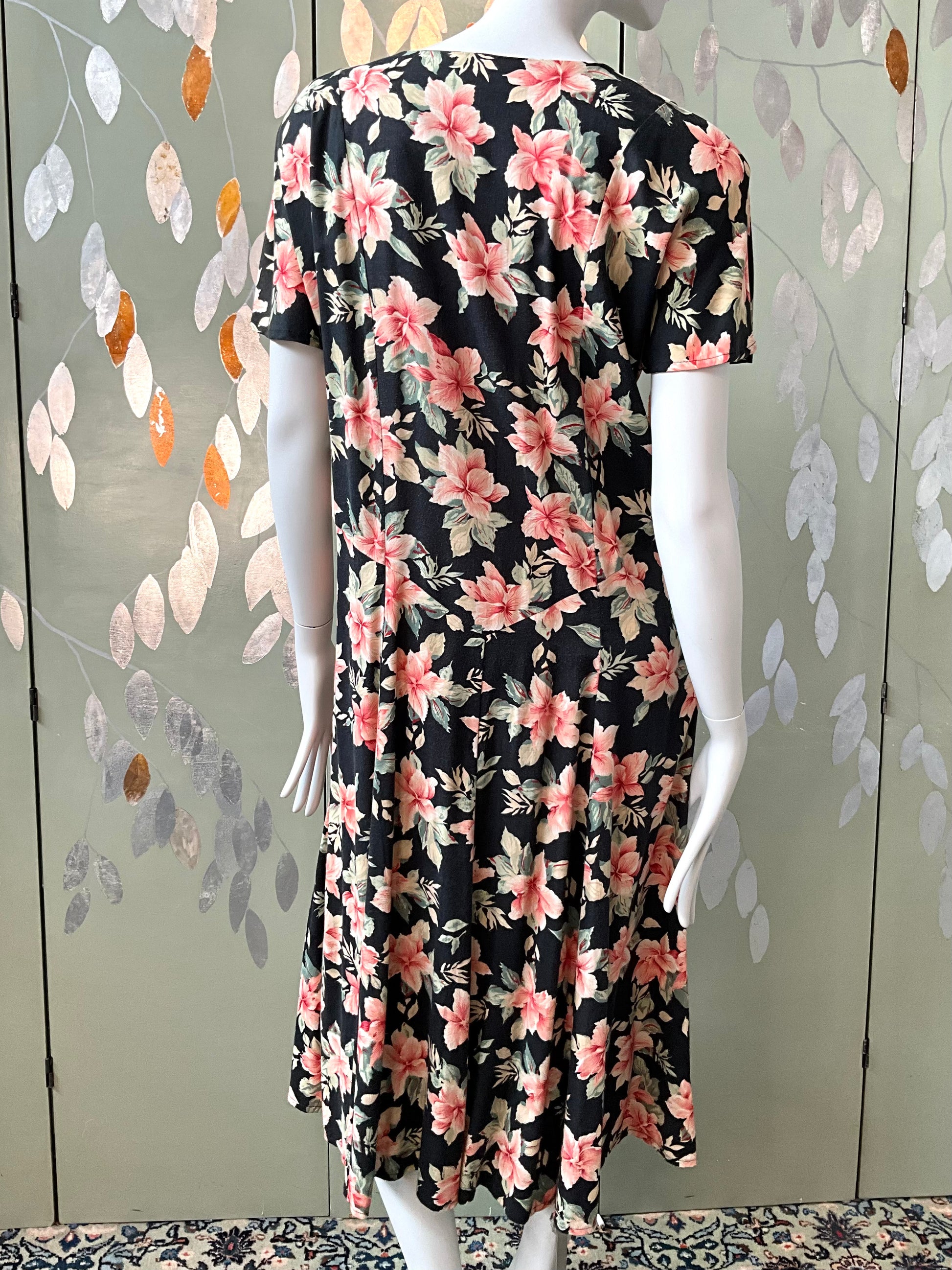 Floral dress on a mannequin against a decorative wall.