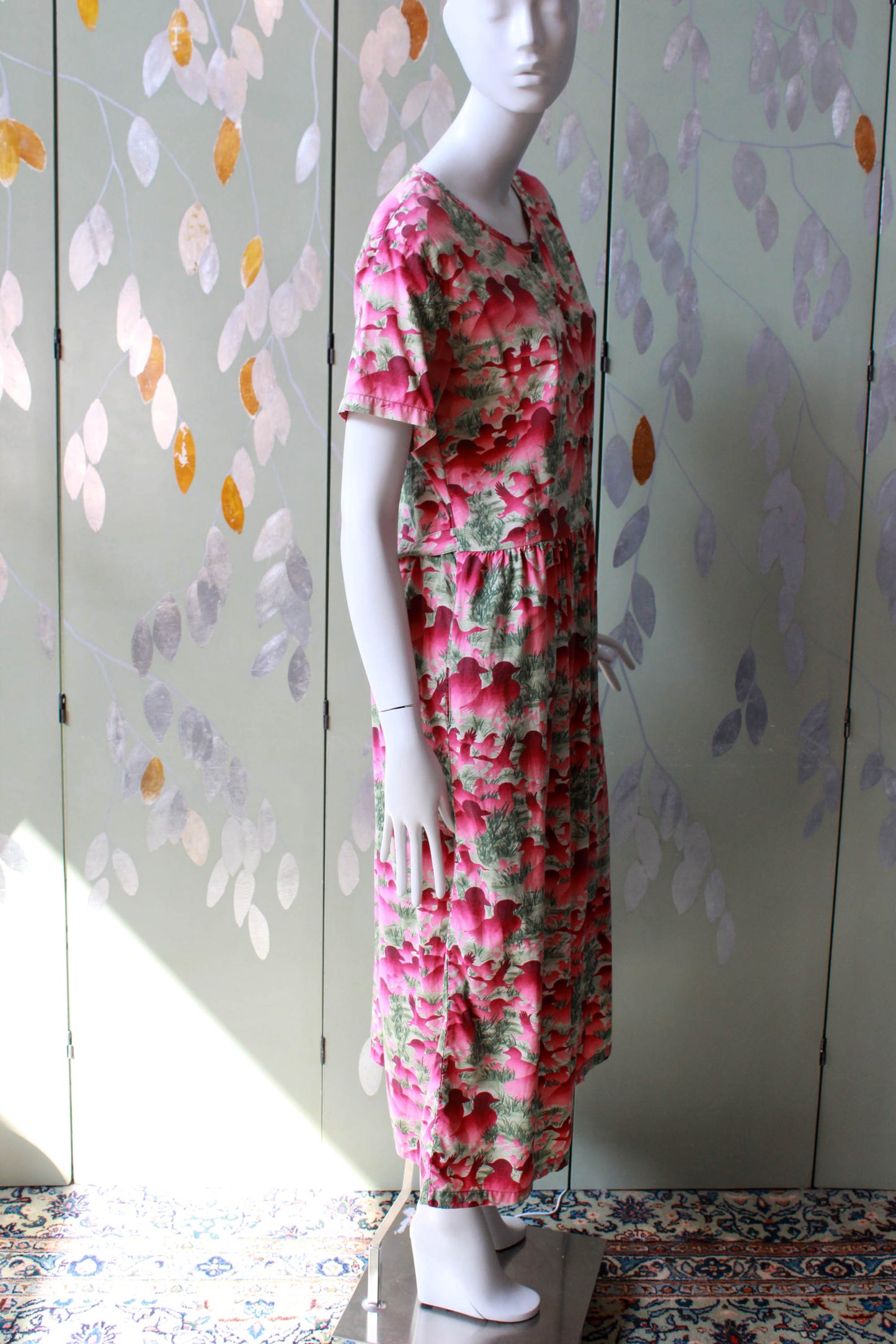 1980s pink duck and bird print against green grass background, short sleeves, button up front, gathered waist midi length skirt with pockets 