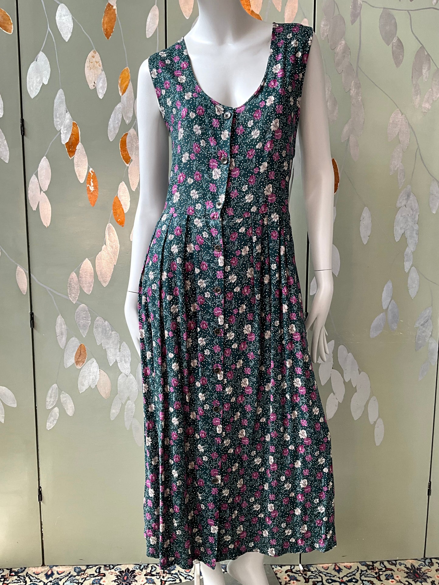 Floral dress on a mannequin against a decorative wall.