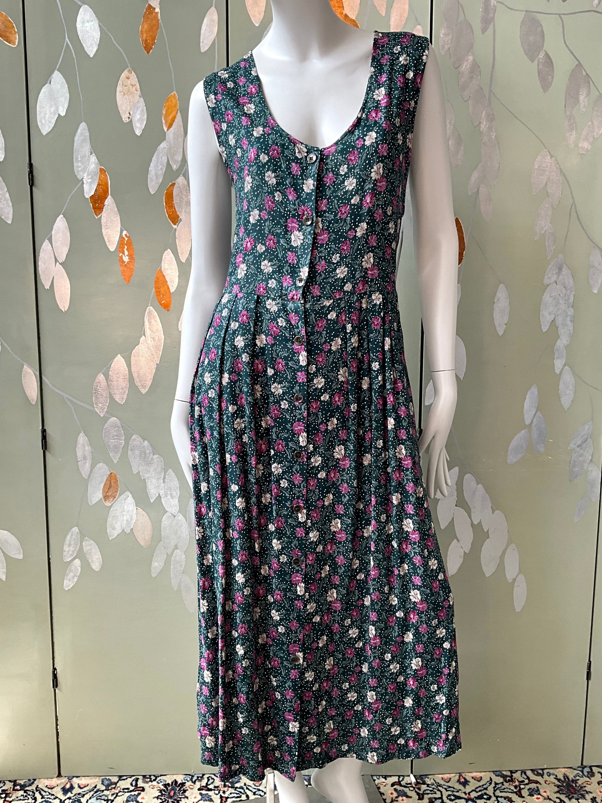 Floral dress on a mannequin against a decorative wall.