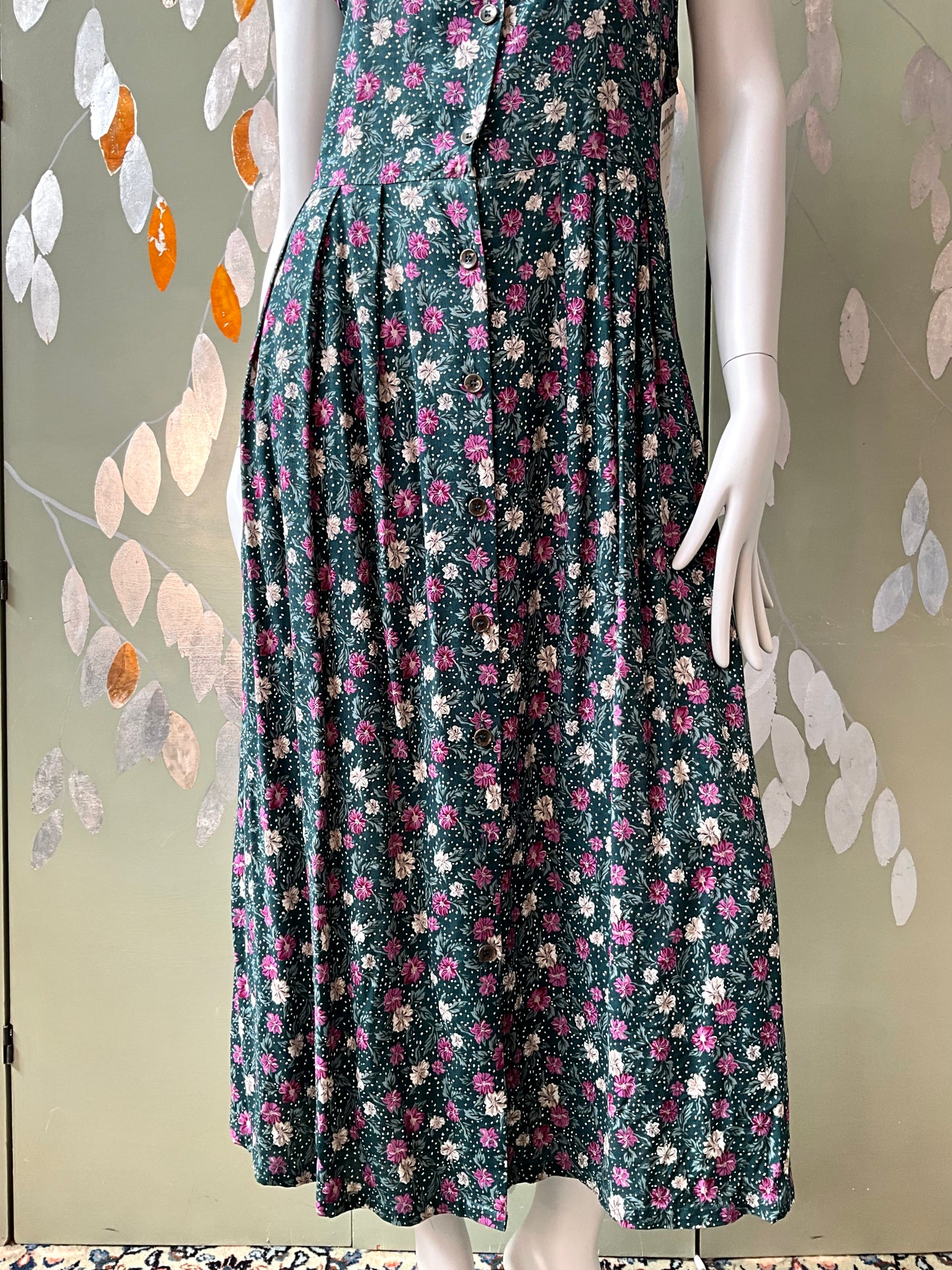 Floral dress on a mannequin against a decorative wall.