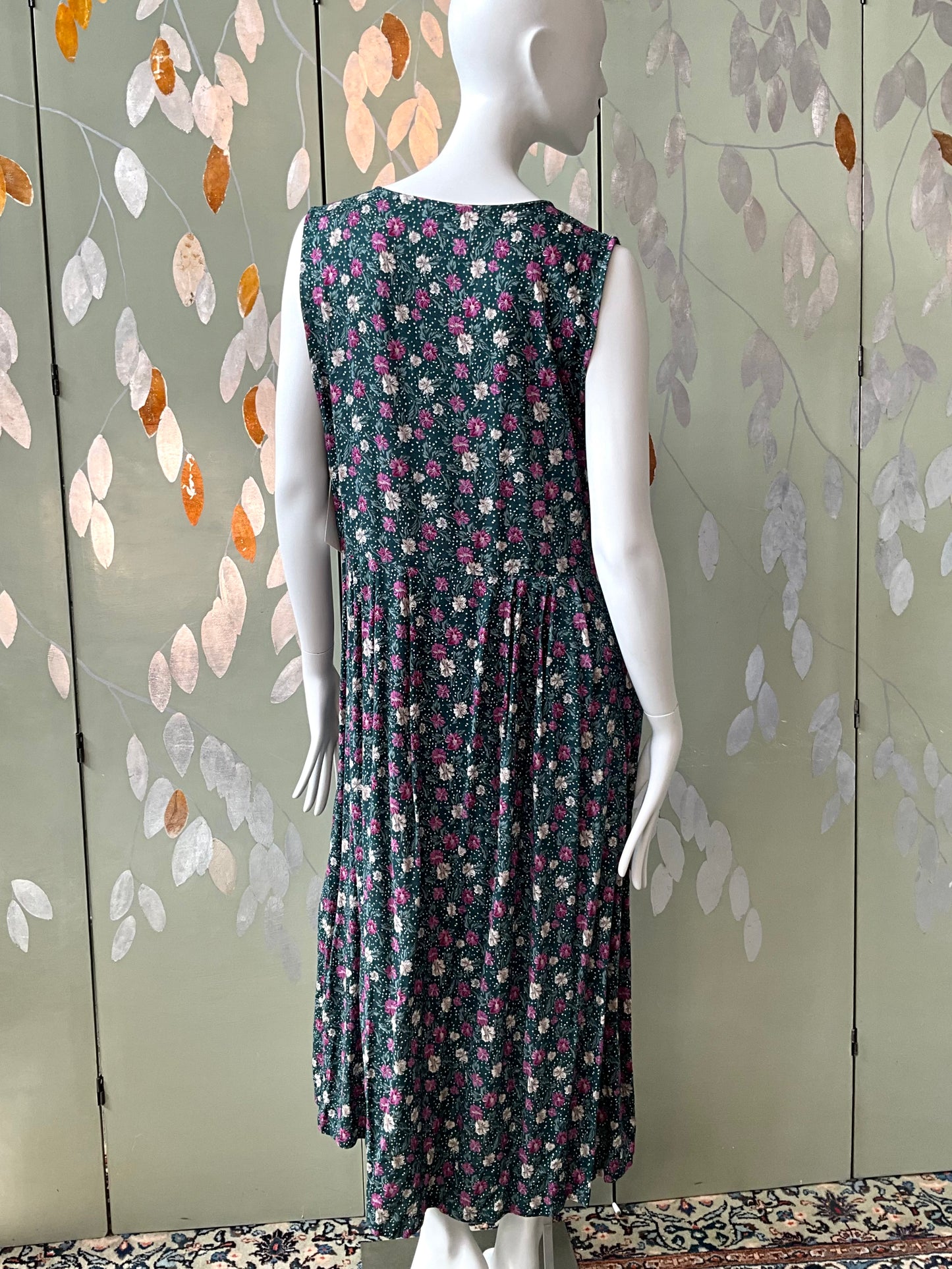 Mannequin wearing a floral dress against a decorative wall.