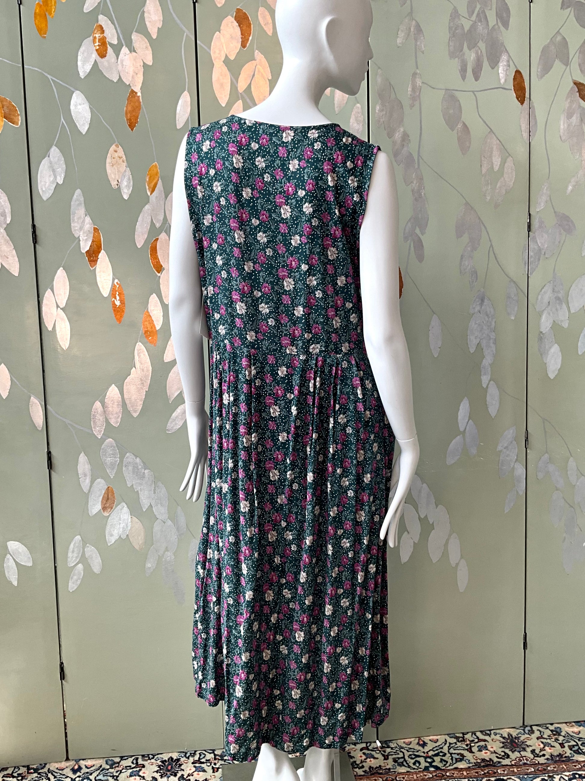 Mannequin wearing a floral dress against a decorative wall.