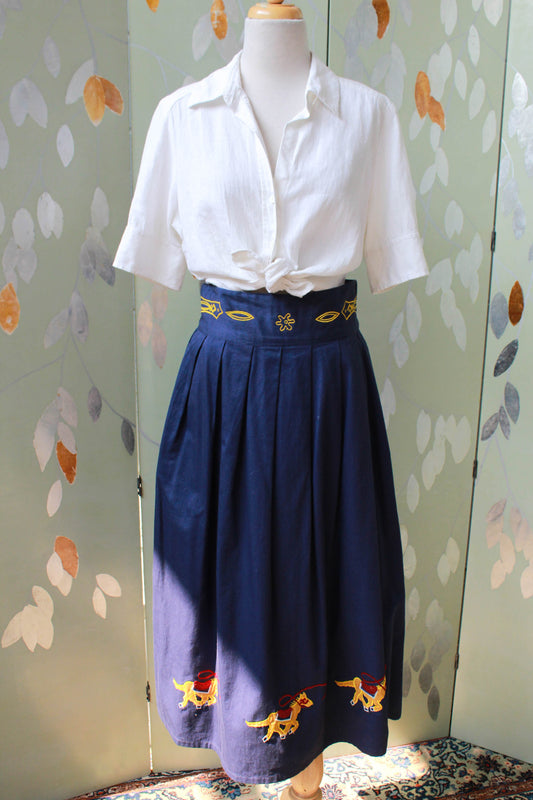 1980s navy blue cotton midi skirt, pleated full skirt with pockets, three gold embroidered horses on the hem and embroidery on the wide waistband