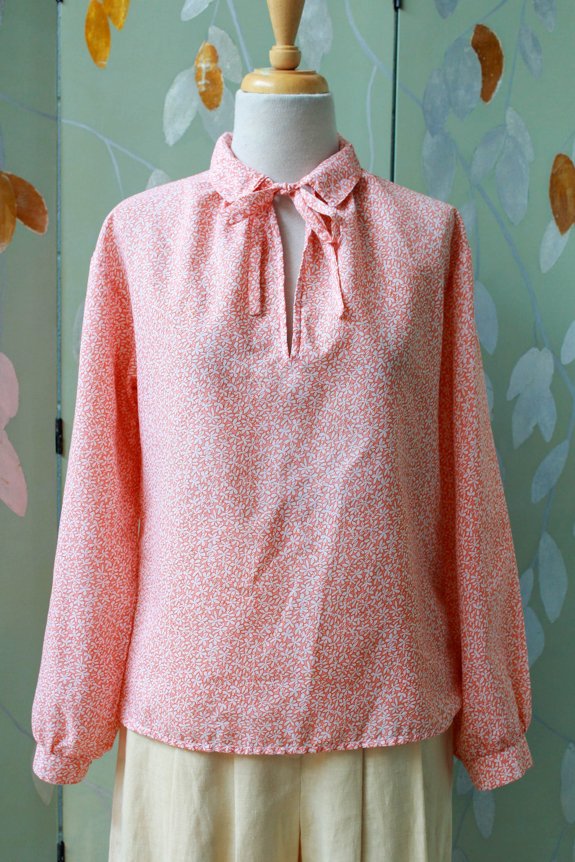 1980s holt renfrew orange and white micro floral print blouse with collar and tie at the neck, long sleeves vintage