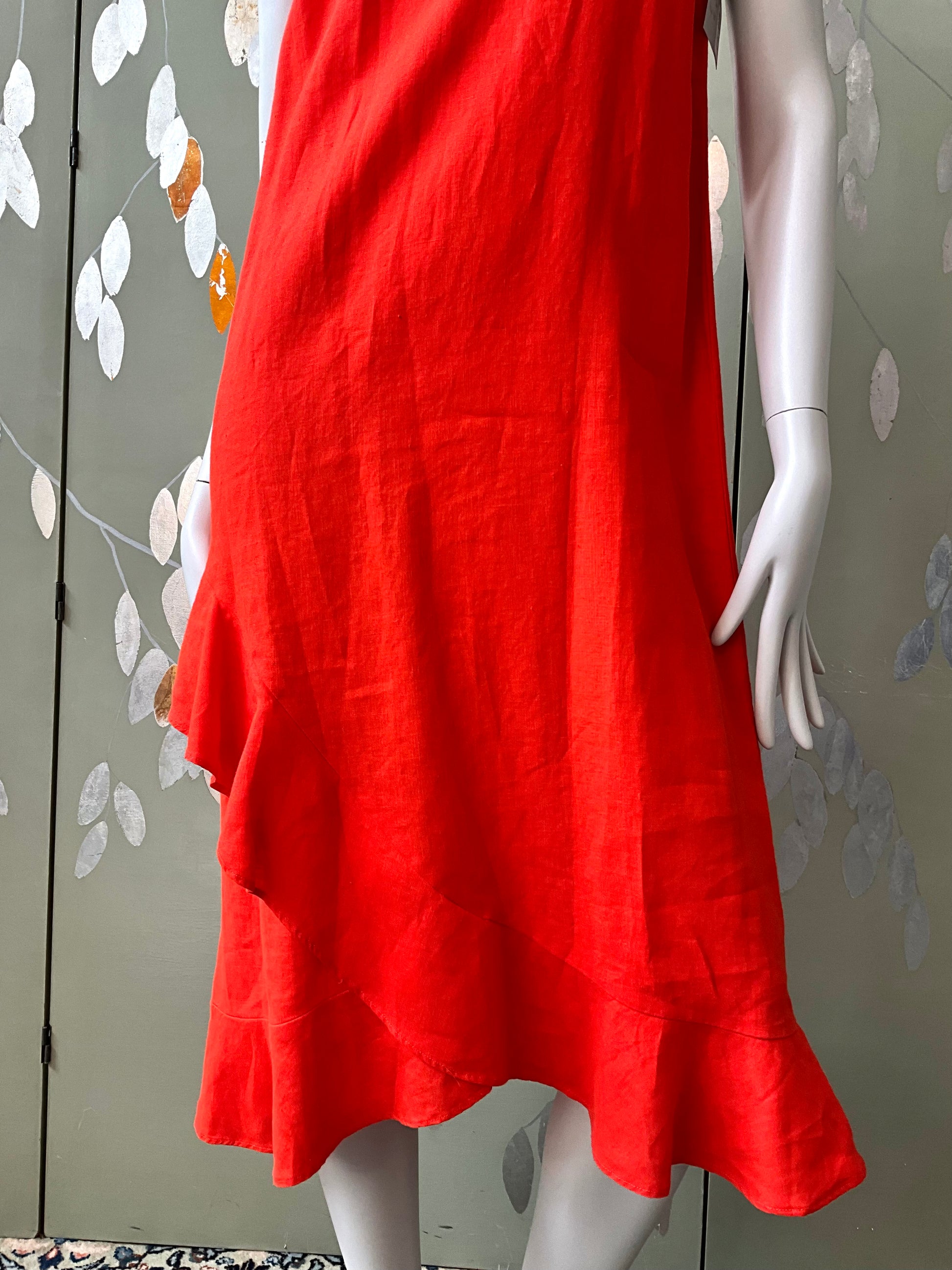 Red dress on a mannequin against a decorative wall.