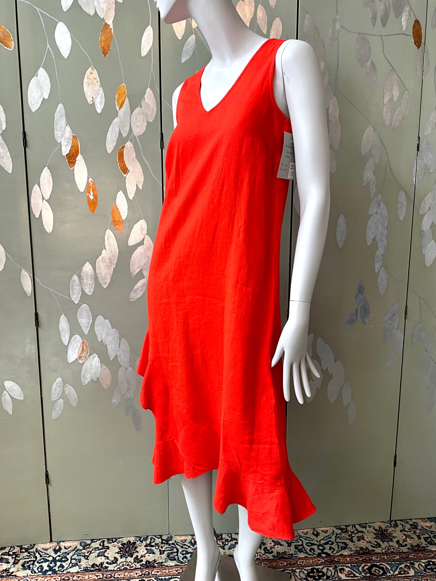 Red dress on a mannequin against a decorative wall.